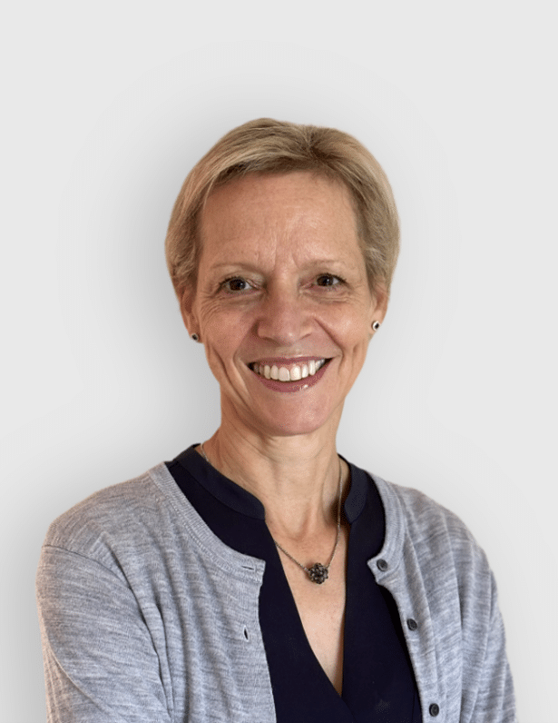 Portrait d'une femme souriante aux cheveux courts, portant un haut noir et un cardigan gris, sur un fond blanc.