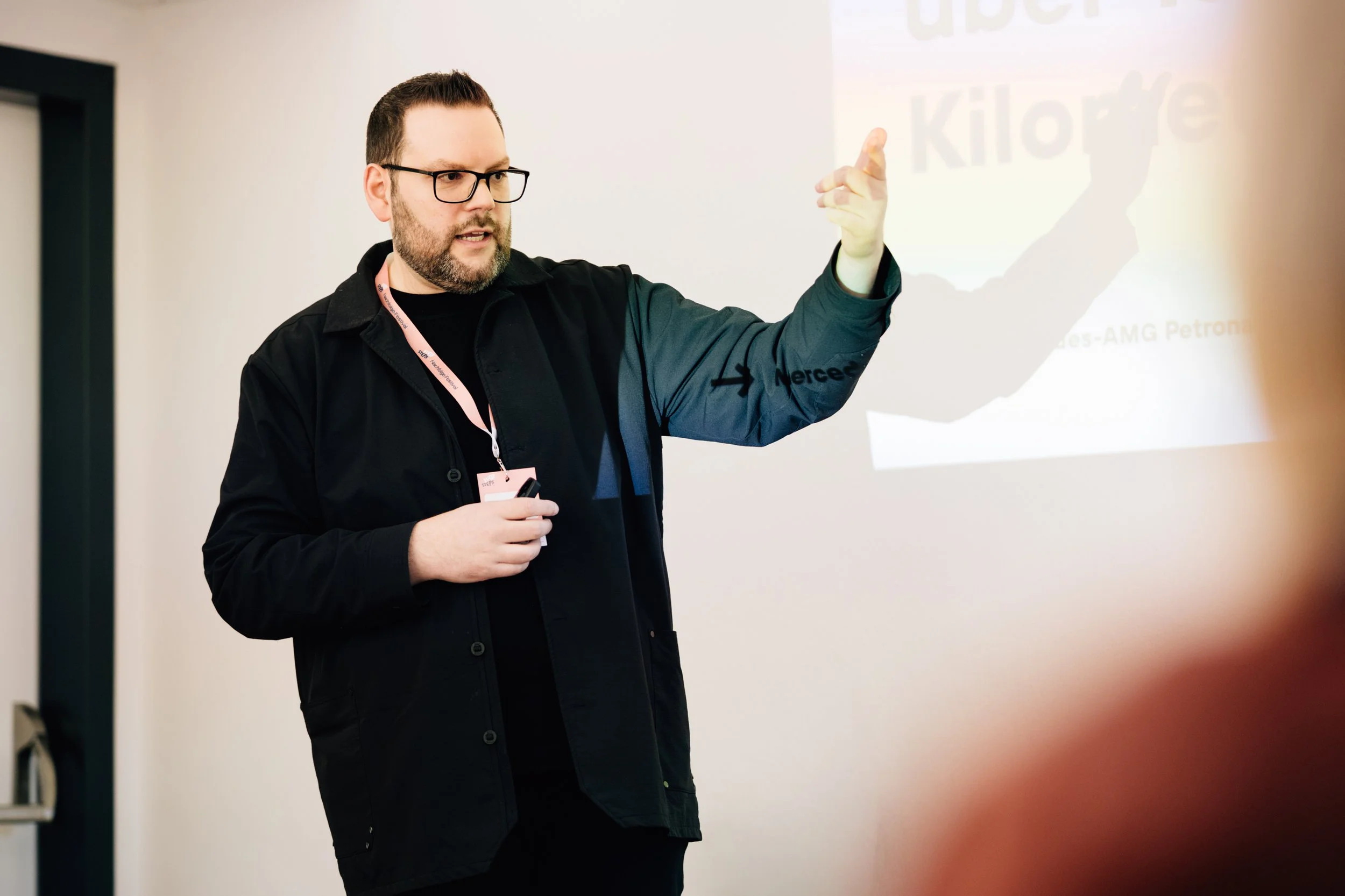 Mann mit Brille, der vor einer Präsentation spricht und auf eine Projektionsfolie zeigt.