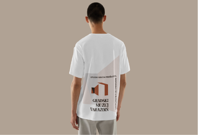 Back of a person wearing a white T-shirt with a logo and text in Serbian for the City Museum of Vranje.