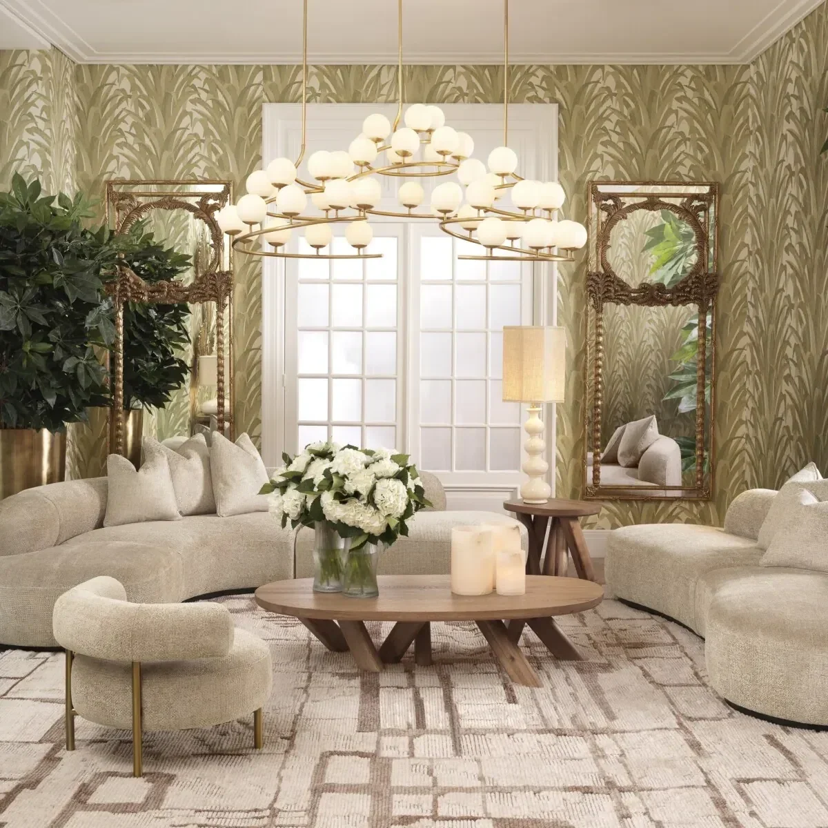 A cozy living room with beige sofas, a wooden coffee table with candles and flowers, a large green plant, a matching side table and lamp, gold framed mirrors, and a modern chandelier with multiple globes, in front of a window with frosted glass.