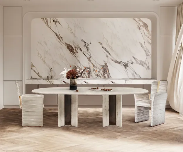 Modern dining room with a marble accent wall, oval dining table, and four textured chairs, decorated with a vase and dried flowers.