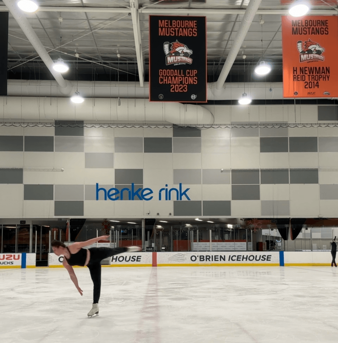 Therapy for teens, young adults, and athletes. A figure skater practicing on the ice rink at Henke Rink in an indoor ice arena, with banners hanging from the ceiling celebrating Melbourne Mustangs' championships and trophies.