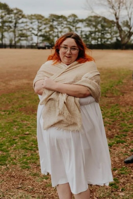 Girl with red hair in shawl and white dress.