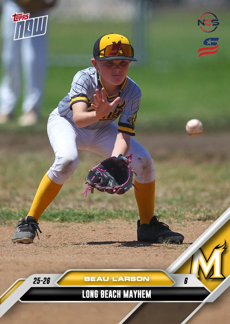 Young boy in a yellow sports uniform with black pinstripes, wearing a black cap with the team logo, standing against a white background.