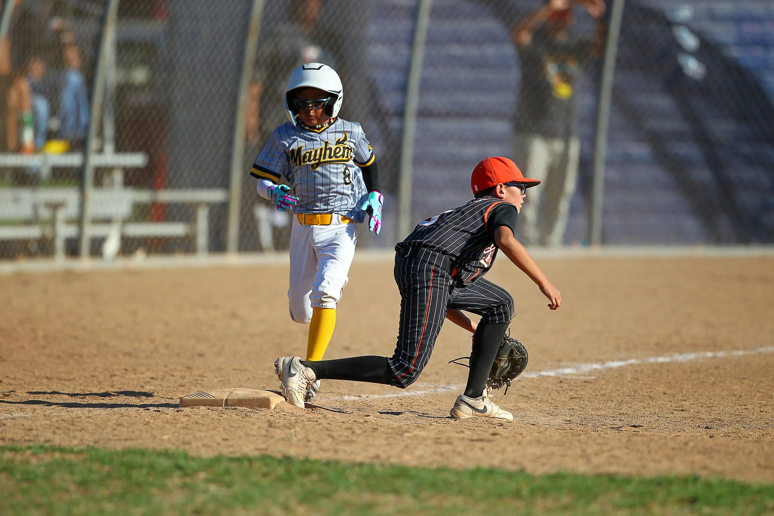 Youth baseball player hustling down the line to beat a ground out to first base.