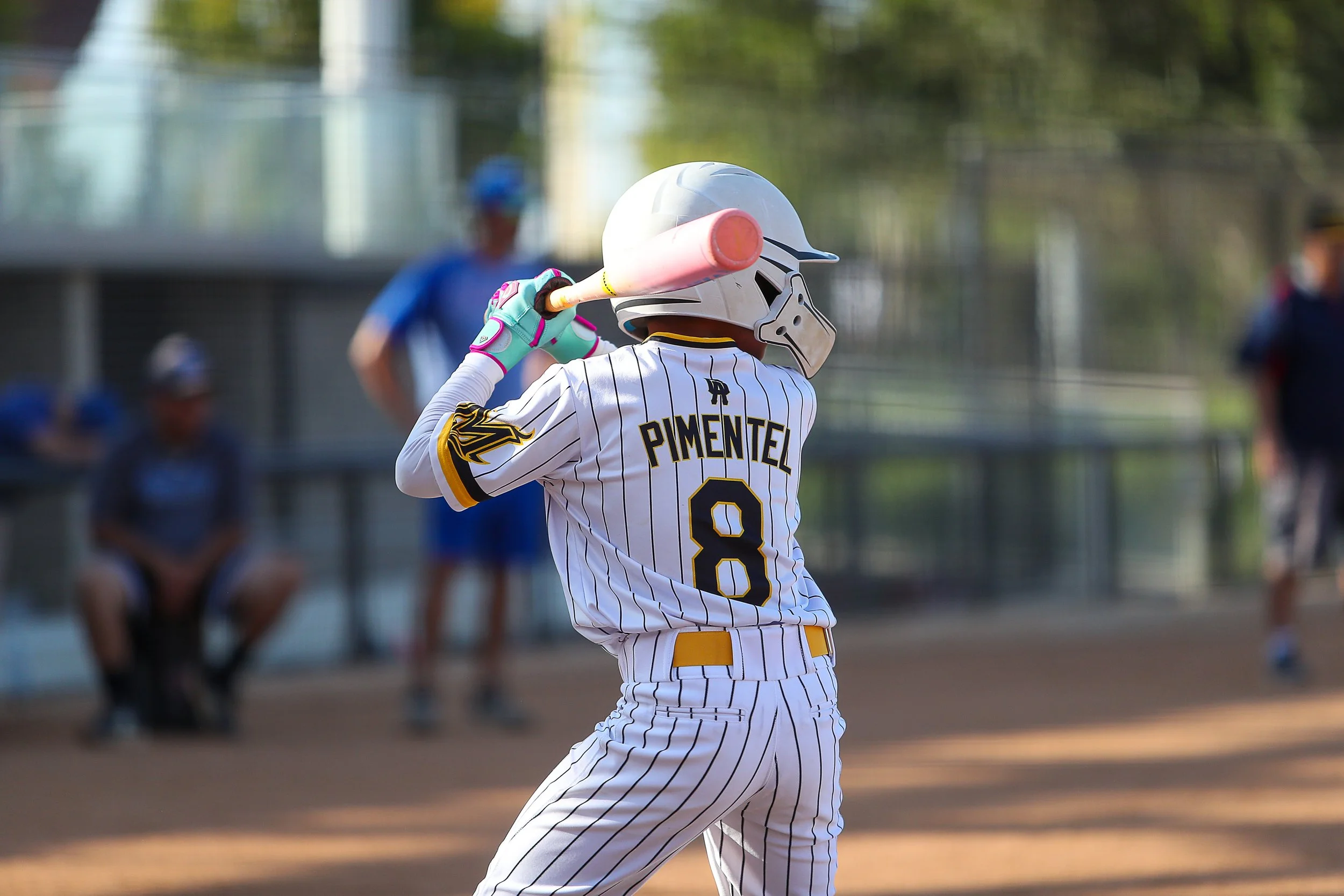 A baseball player in a white pinstripe uniform with the name 'Pimentel' and number 8 on the back, wearing a helmet and gloves, holding a bat ready to swing on a baseball field.