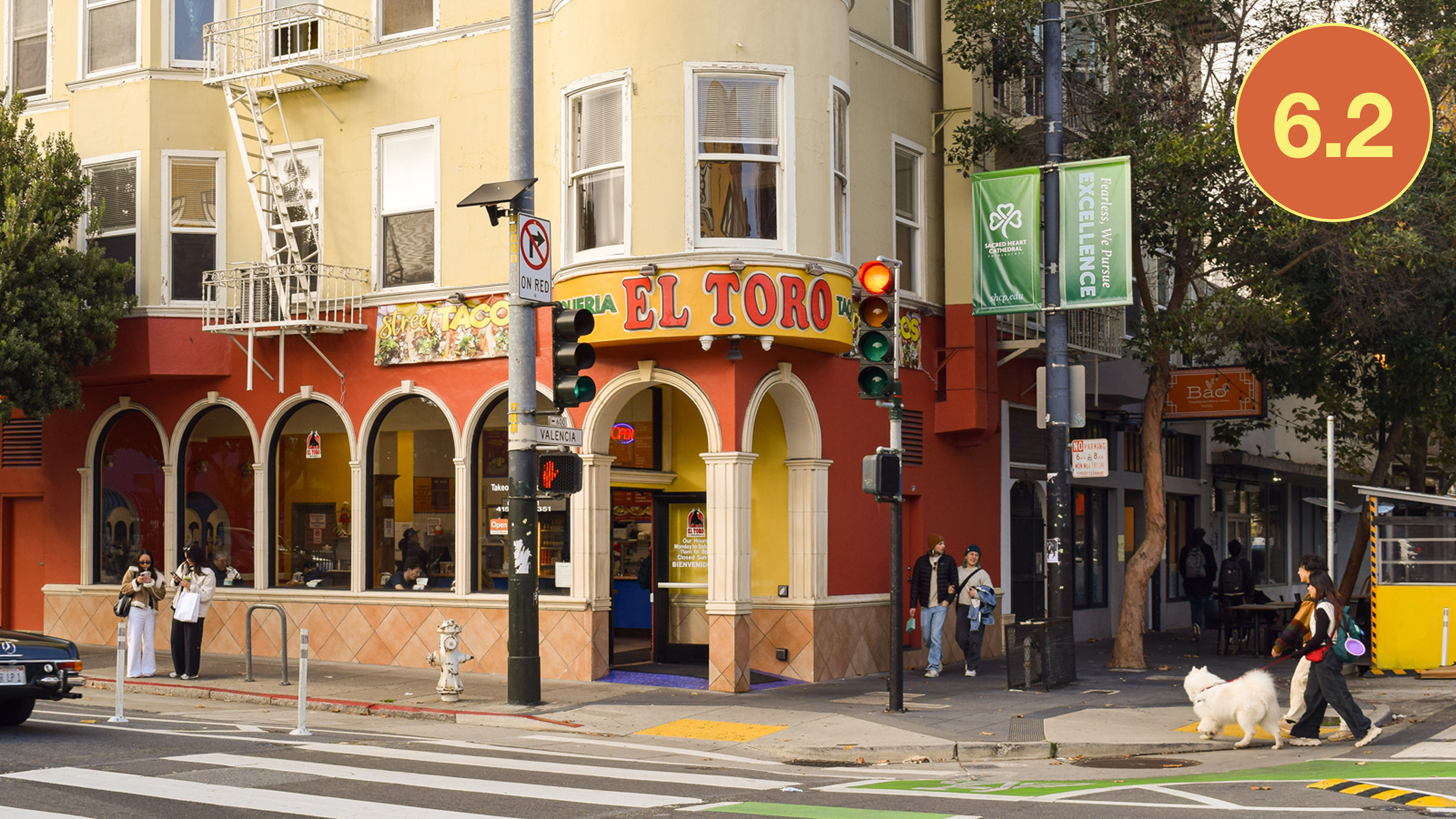 Exterior of El Toro Taqueria on Valencia Street in San Francisco, showing its bright yellow facade, corner entrance, and people ordering outside.