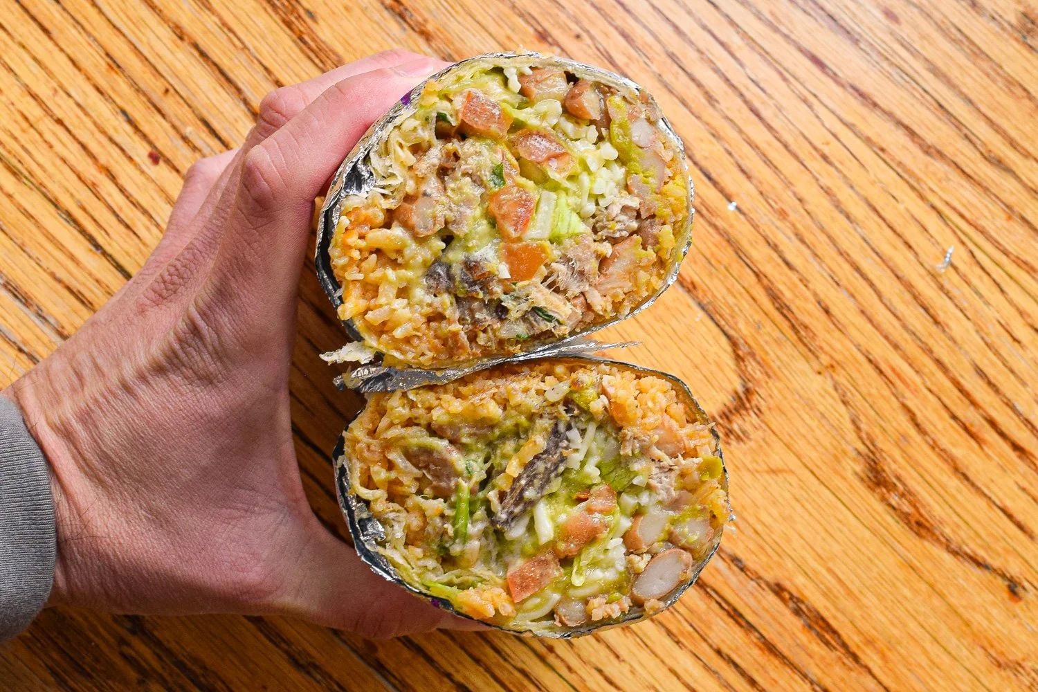 Close-up of a cut Super Carnitas burrito from El Toro Taqueria, showing carnitas, guac, cheese, and balanced fillings.