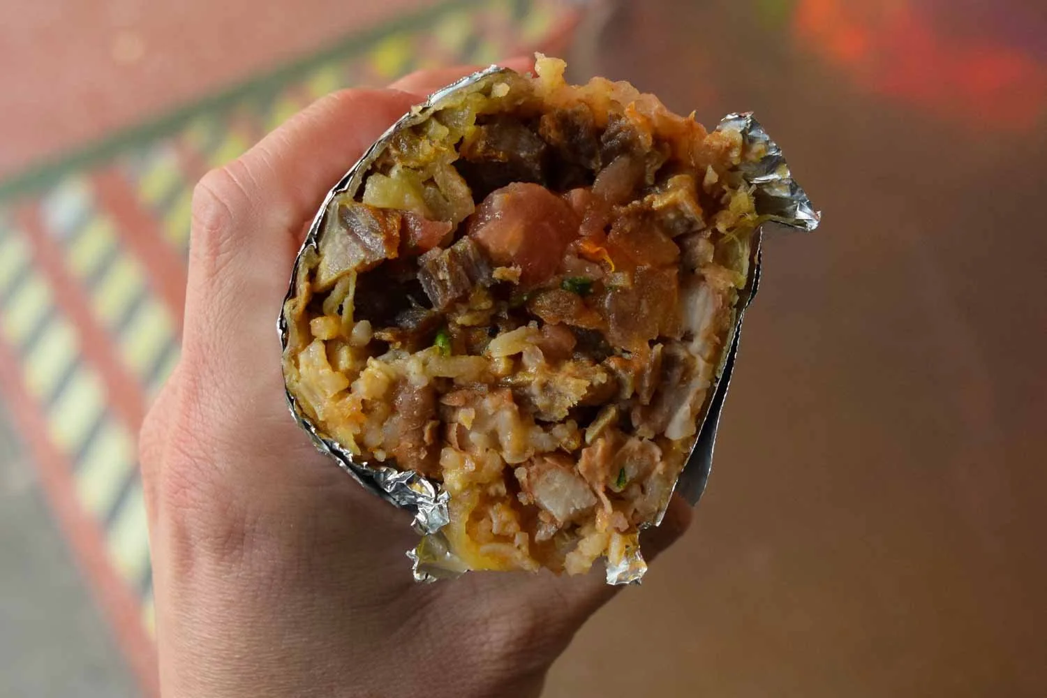 Chicharrones burrito cross section from La Palma Mexicatessen showing pork, rice, pico-style salsa, and fillings wrapped in a homemade tortilla