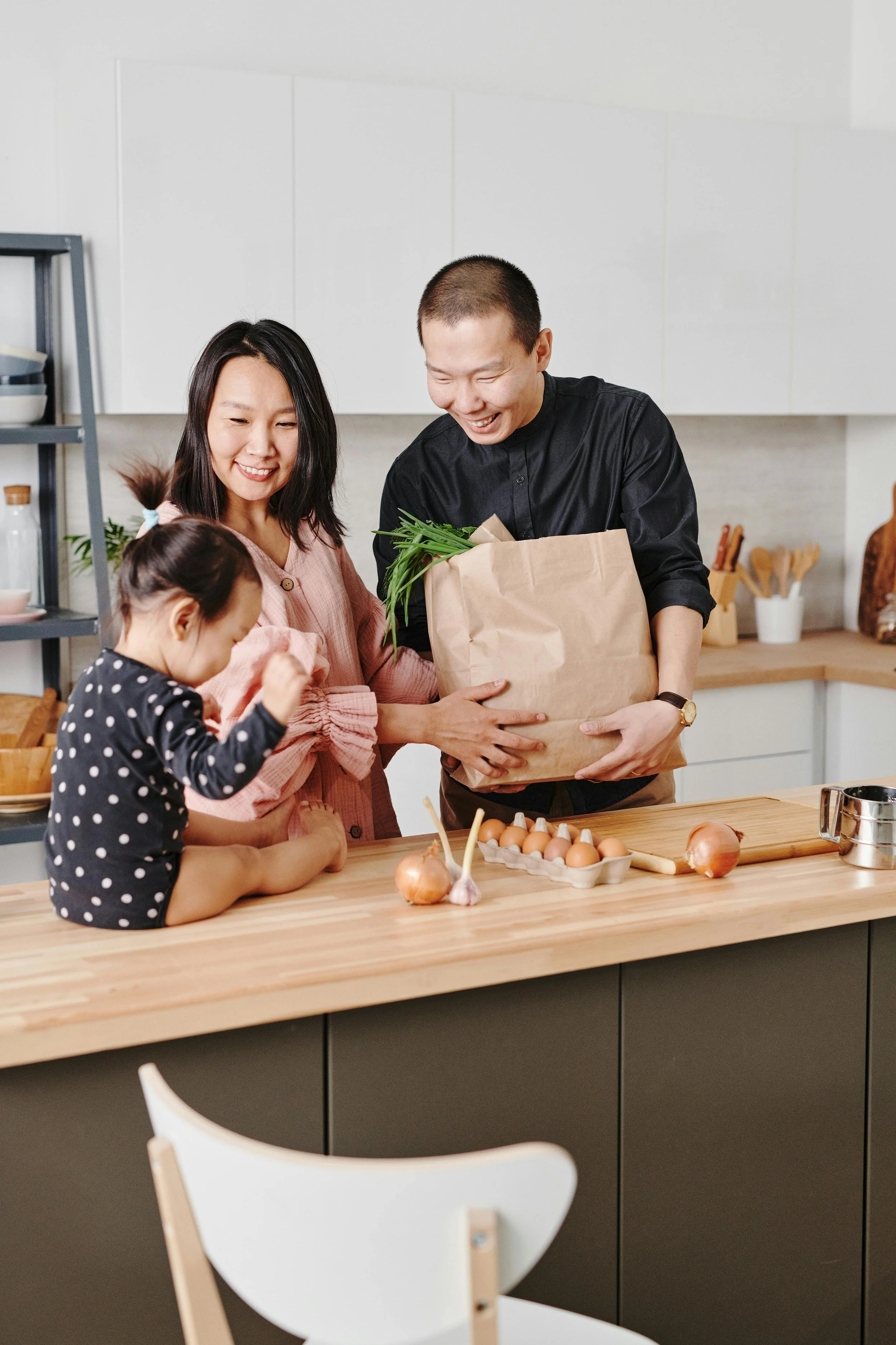 A family cooking together in the kitchen with eggs and fresh vegetables, illustrating a family nutritionist and pediatric dietitian’s focus on fun, festive, healthy meals for kids.