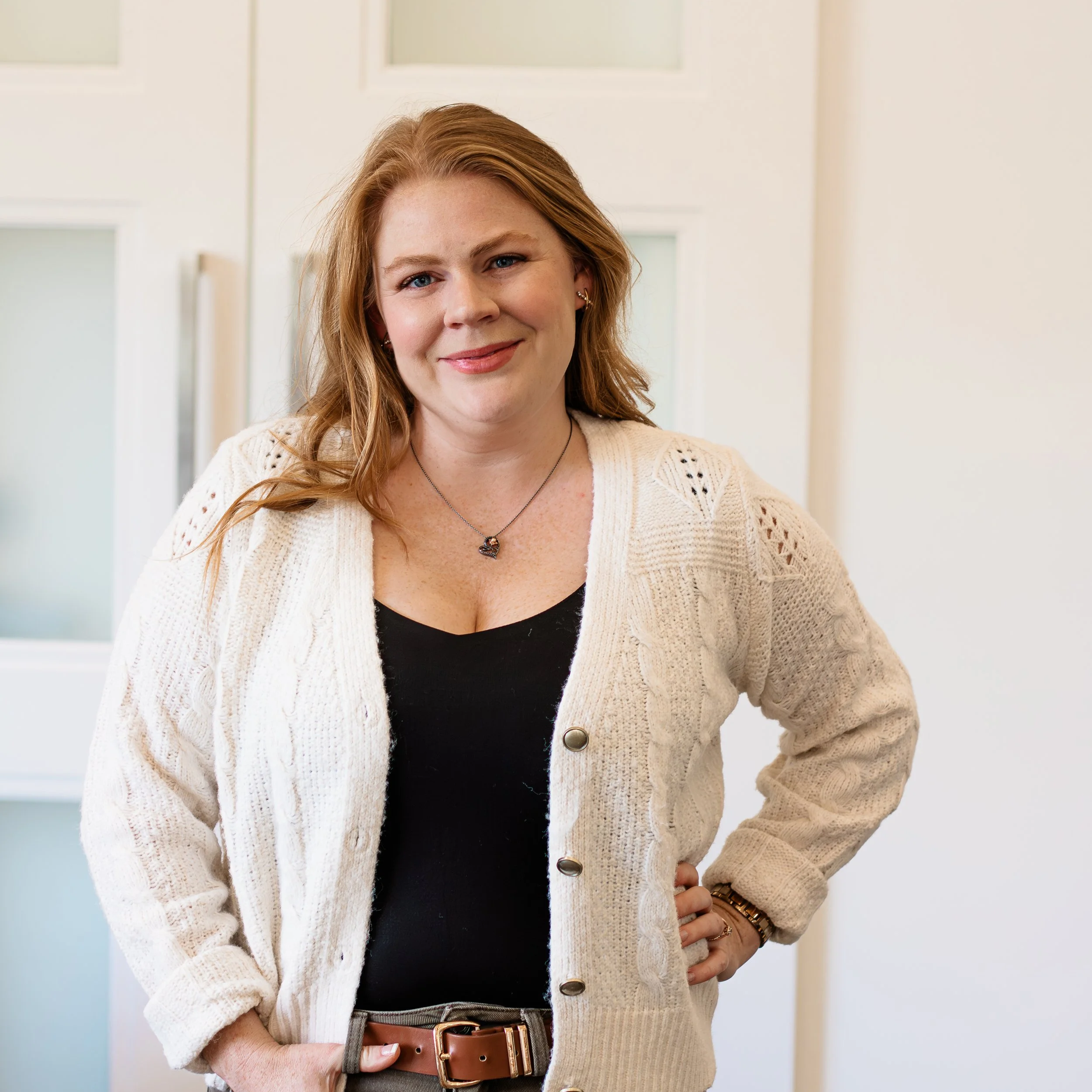 A pediatric dietitian and family nutritionist with red hair and a warm smile standing indoors, offering kids and family nutrition counseling for parents seeking a childrens nutritionist.