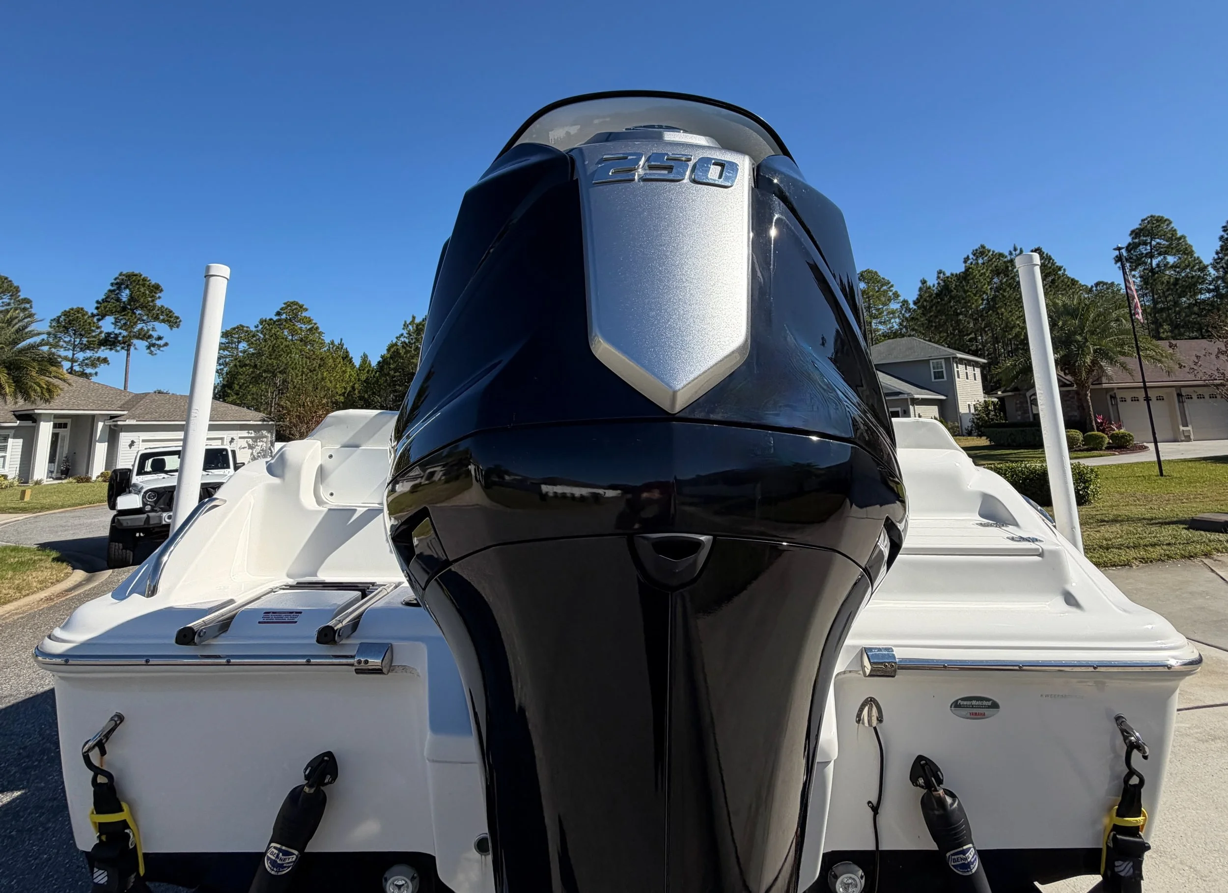 Front view of a boat with a black outboard motor in a residential neighborhood.