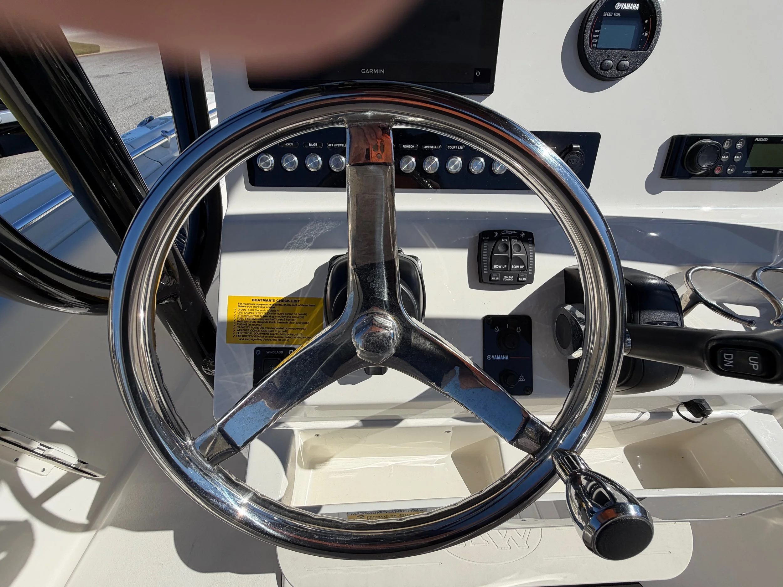 Boat dashboard with steering wheel, electronic gauges, and control switches.