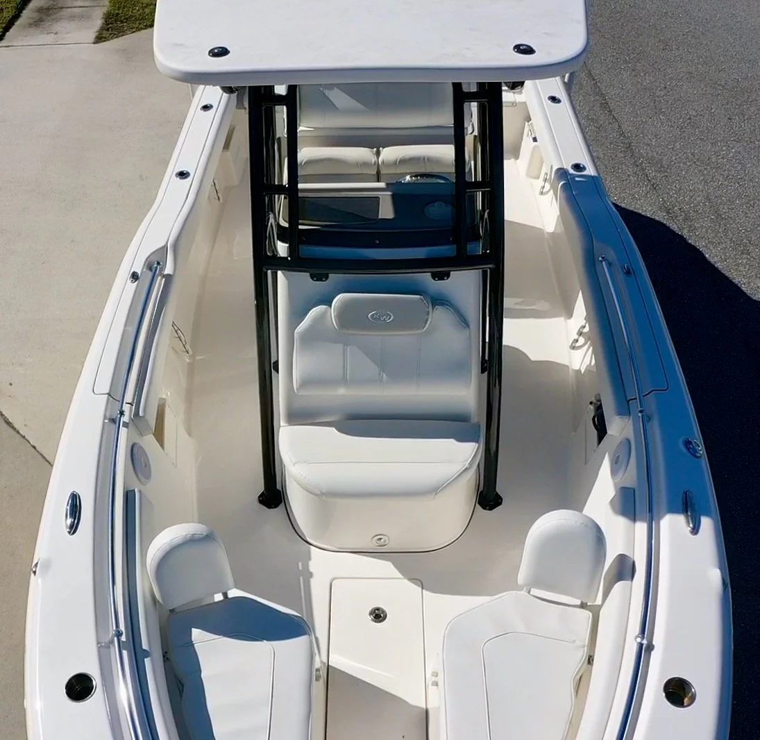 Top-down view of a white boat with seating, a steering console, and a black frame structure.