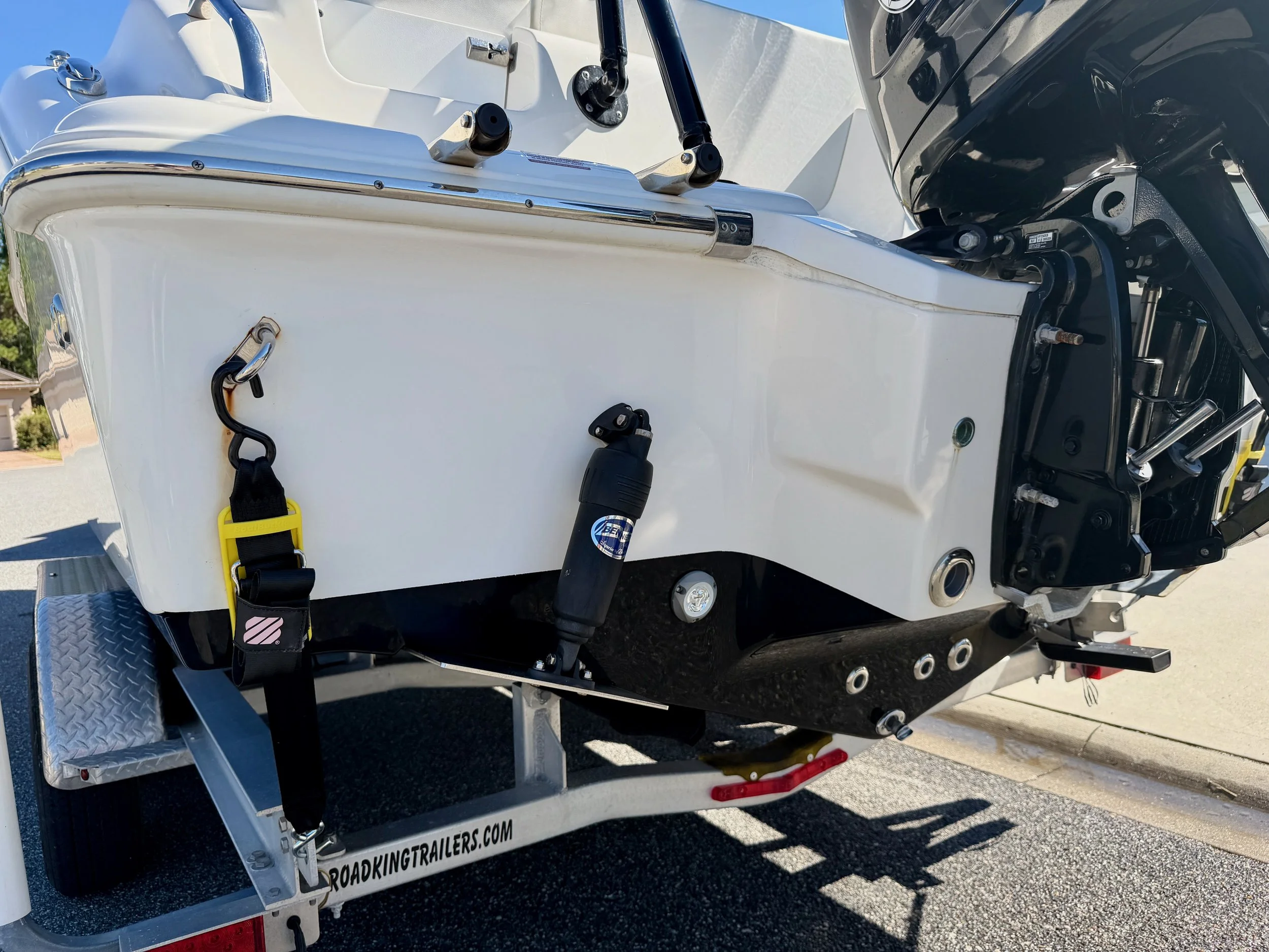 Boat on a trailer with a mounted outboard motor, hydraulic lift, and safety straps.