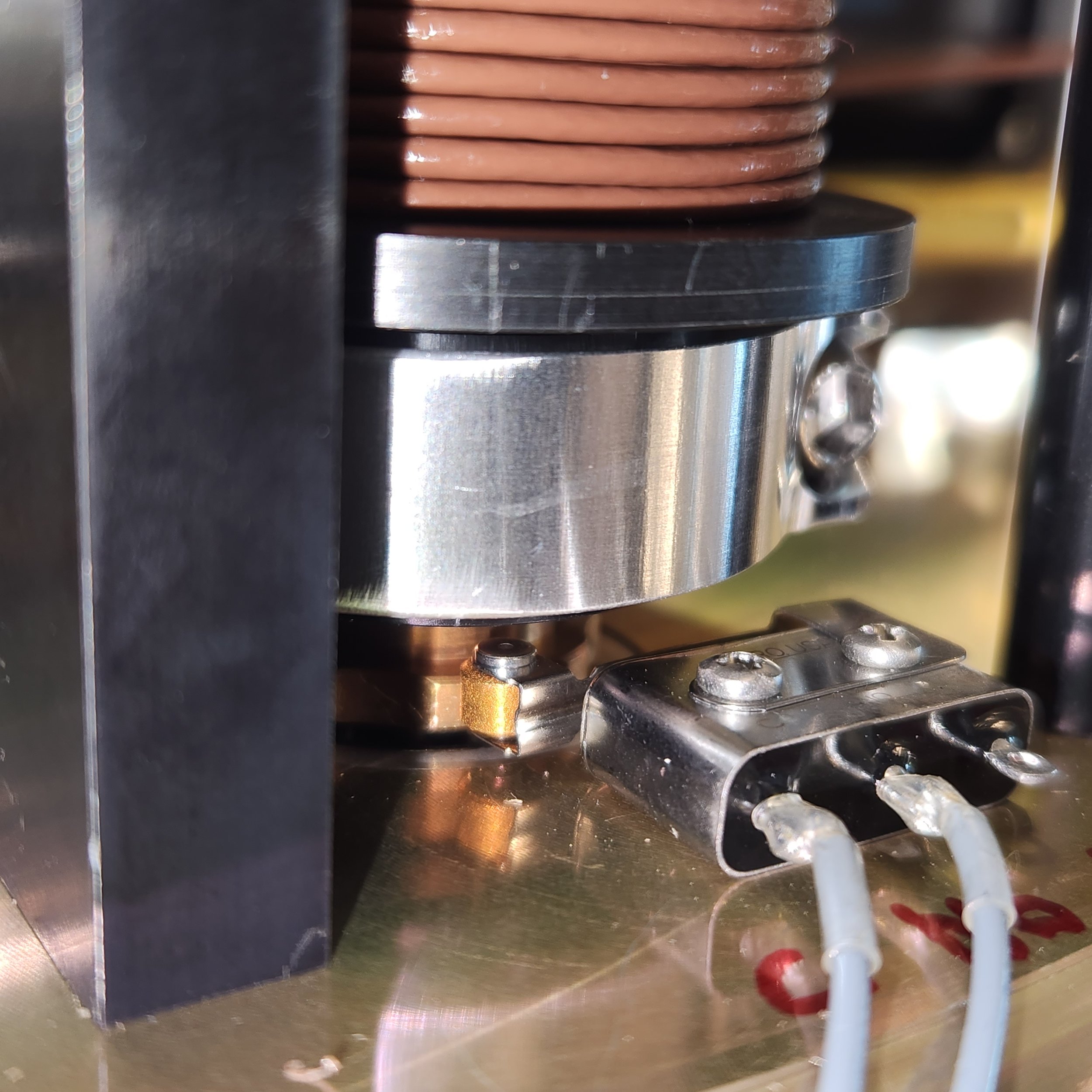 Close-up of a mechanical device with metal and copper parts, wires, and screws