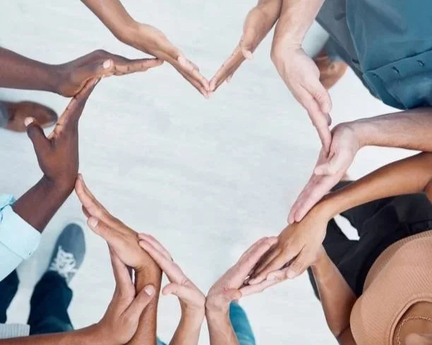 Multiple hands forming a heart shape from different directions.