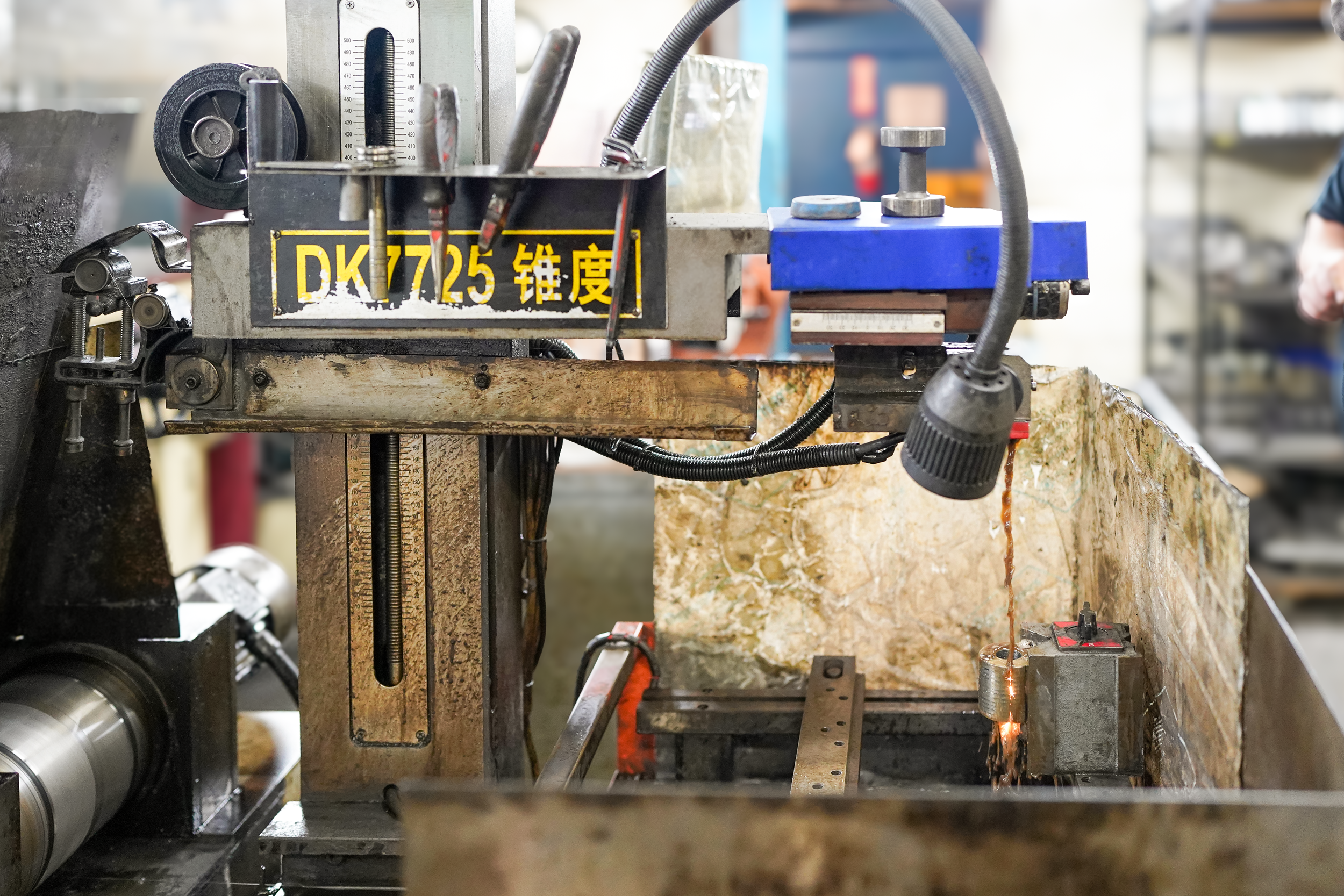 A machine used for industrial cutting or welding, with various mechanical parts, gauges, and a bright sparks near a metal piece being worked on.