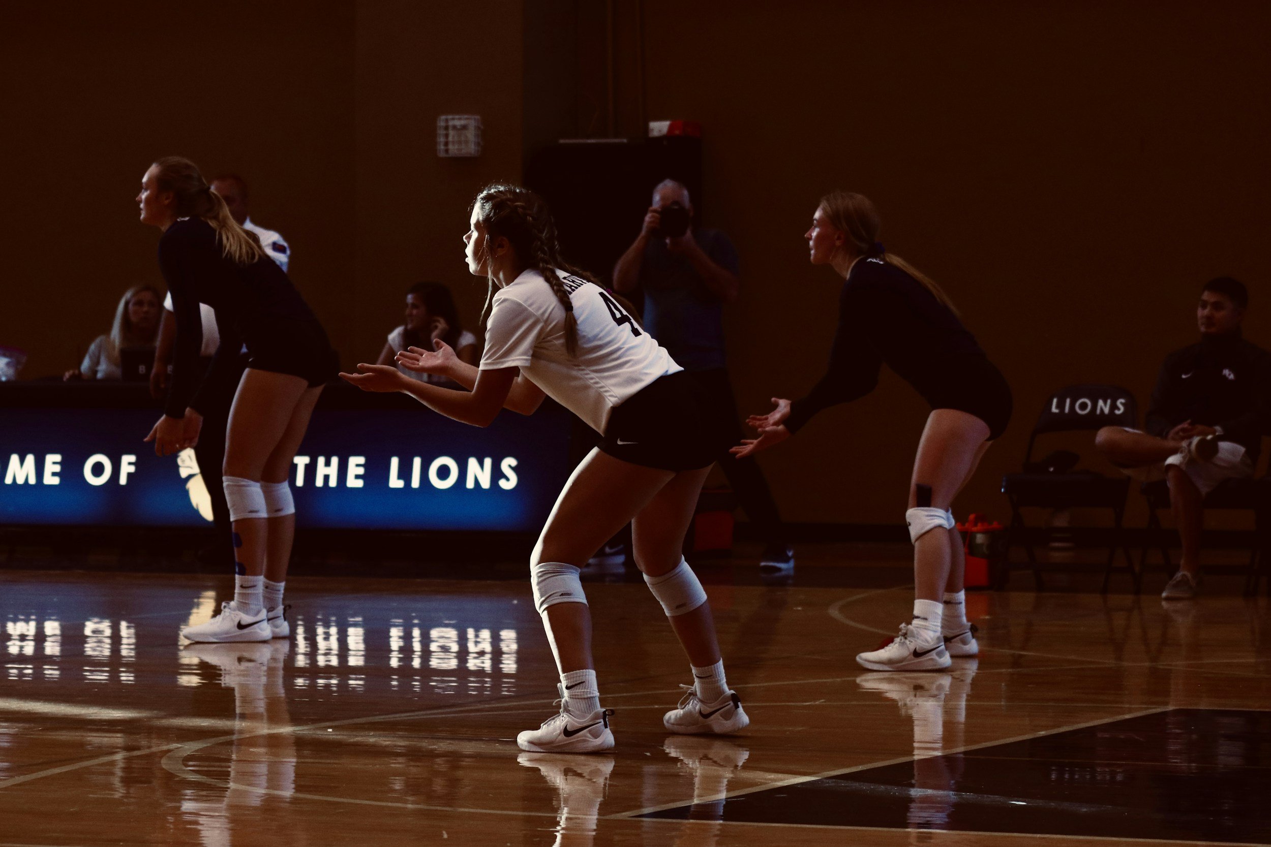 Volleyball players in black and white uniforms practicing on an indoor court.