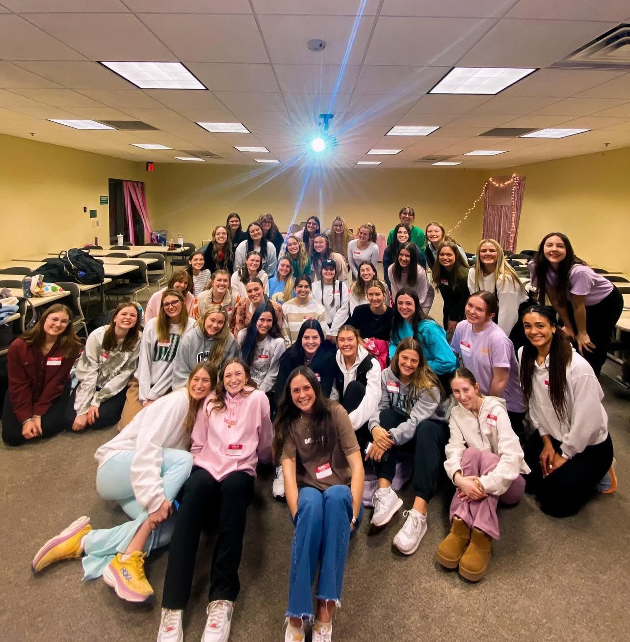 Group of young women posing for a photo with some decorations in the background.