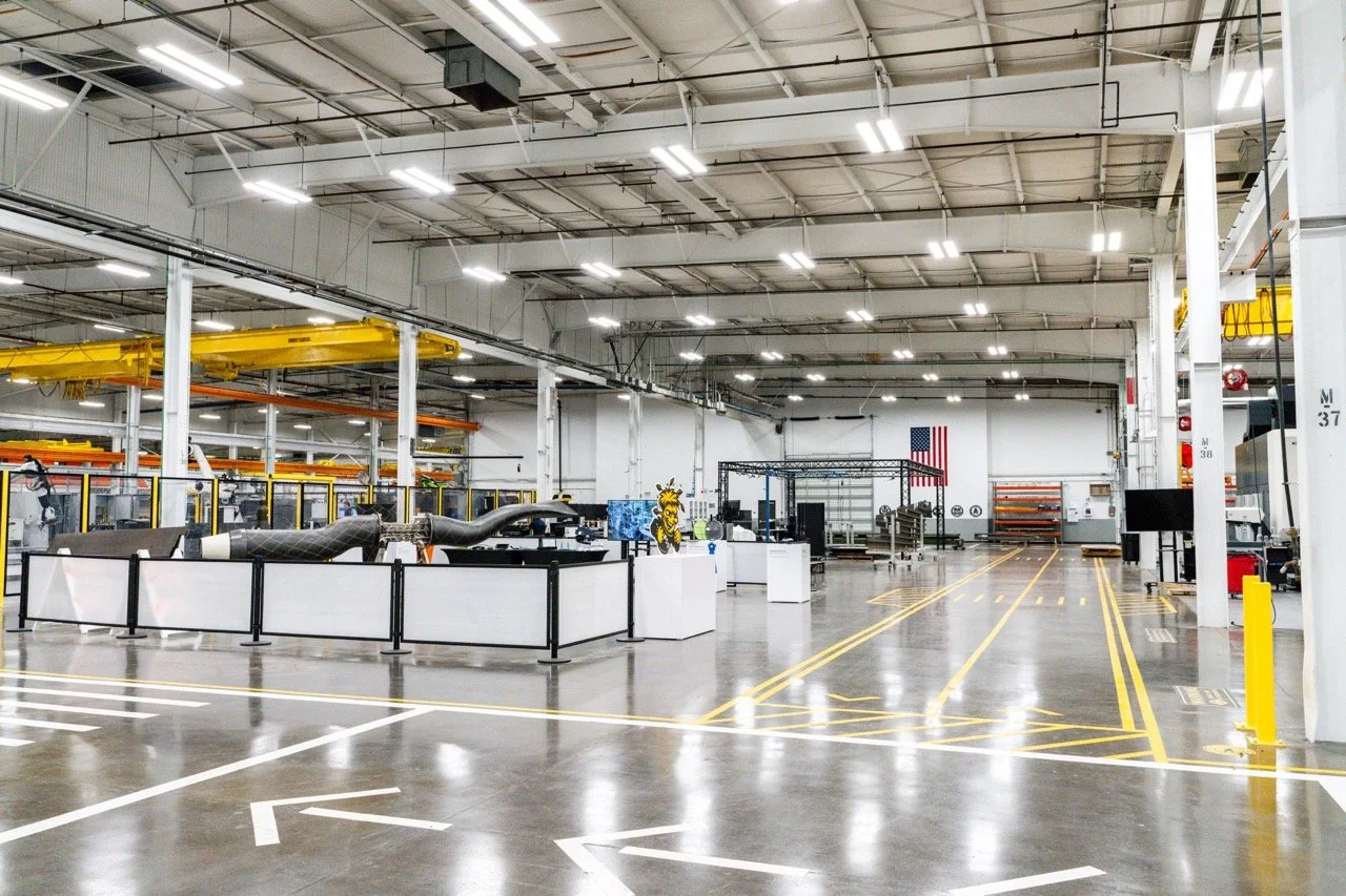 Empty industrial manufacturing or warehouse space with machinery and American flag in the background.
