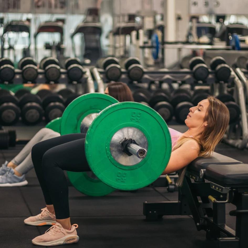 Mujer haciendo peso muerto con barra en gimnasio.