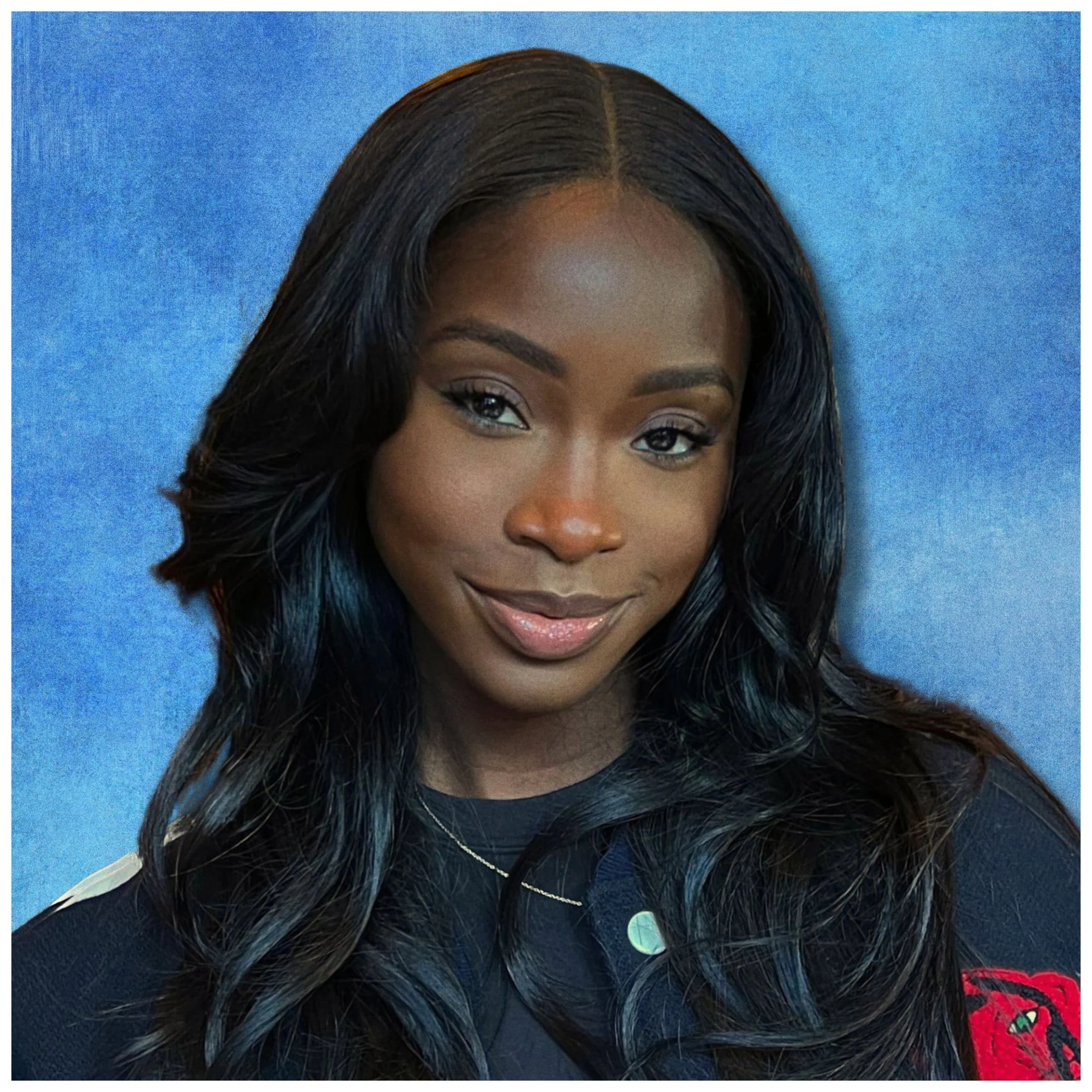 A young African American woman with long wavy black hair, smiling softly, wearing a black top with a red logo on the sleeve, against a blue background.