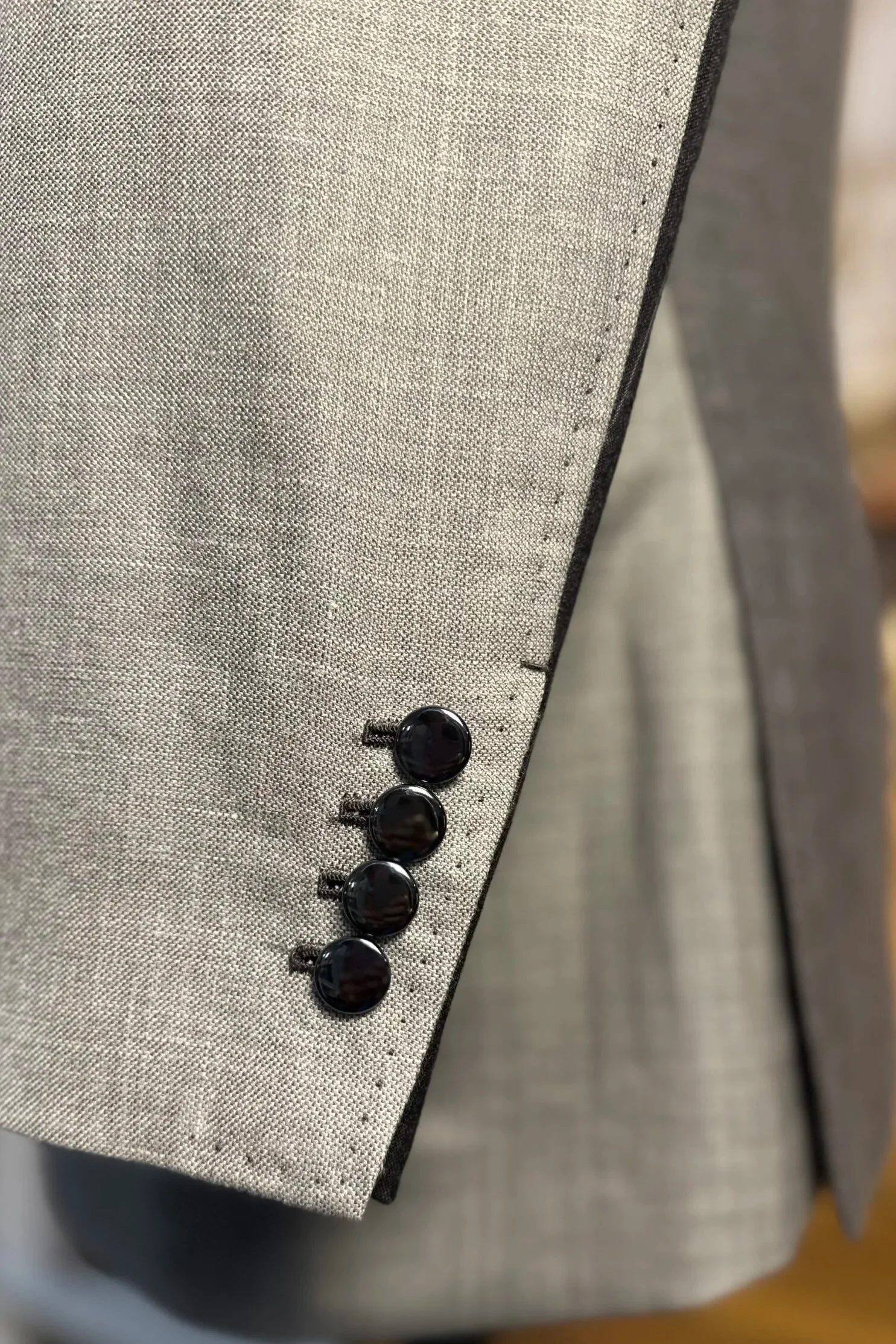 Près d'un pantalon gris avec boutons noirs, la texture du tissu est visible.