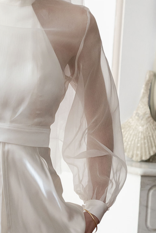 Veste ou robe blanche en satin avec une manche en tulle transparent.