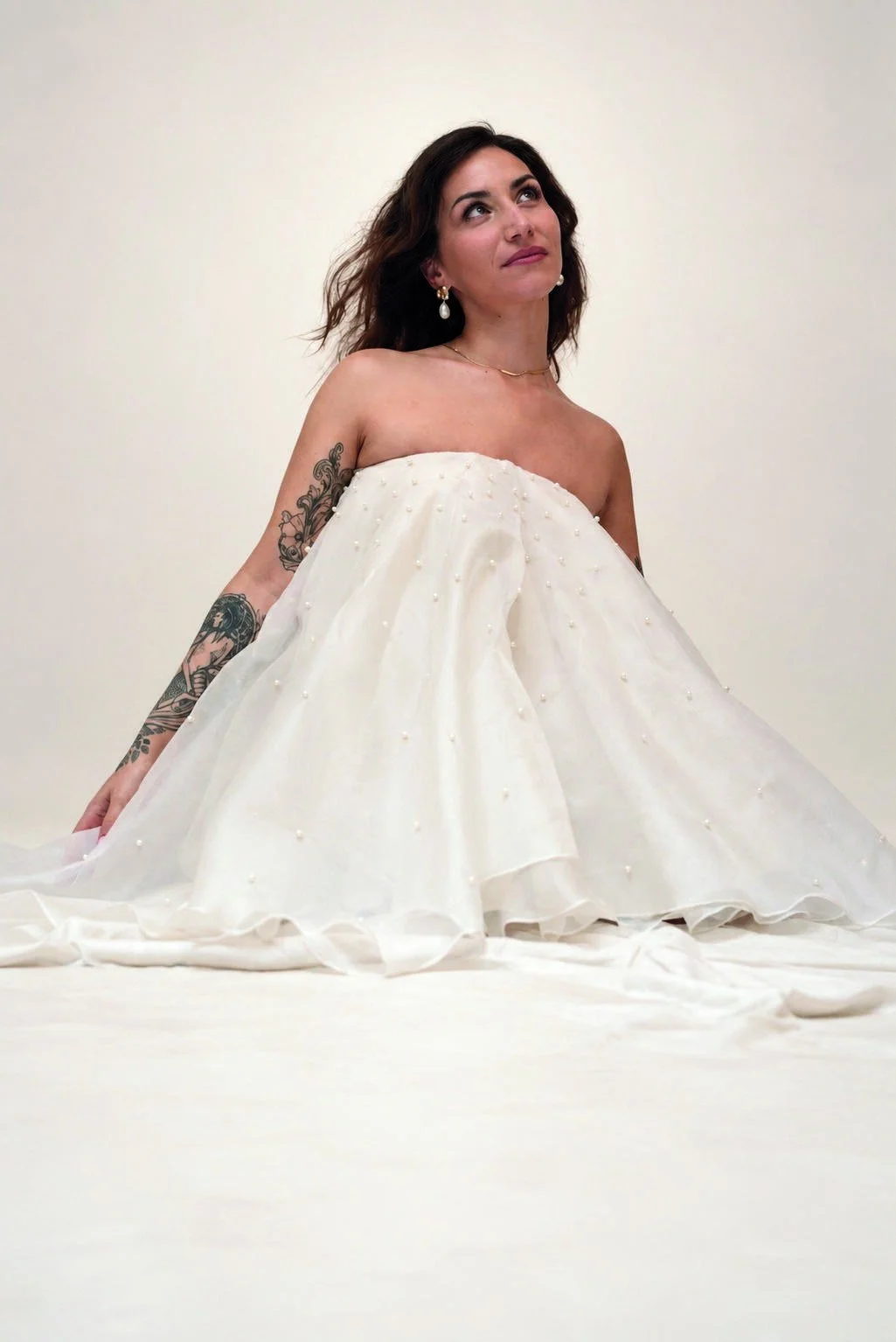 12 — PÉNÉLOPE · Le fil
La mariée de la collection associe une coupe bustier à l’organza ivoire. Les perles cousues à la main et les superpositions célèbrent la patience du geste.