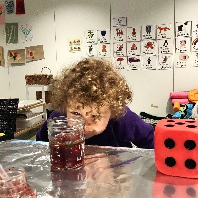 Child taking part in a science experiment, in a nursery classroom with educational posters on the wall. Finchley London.