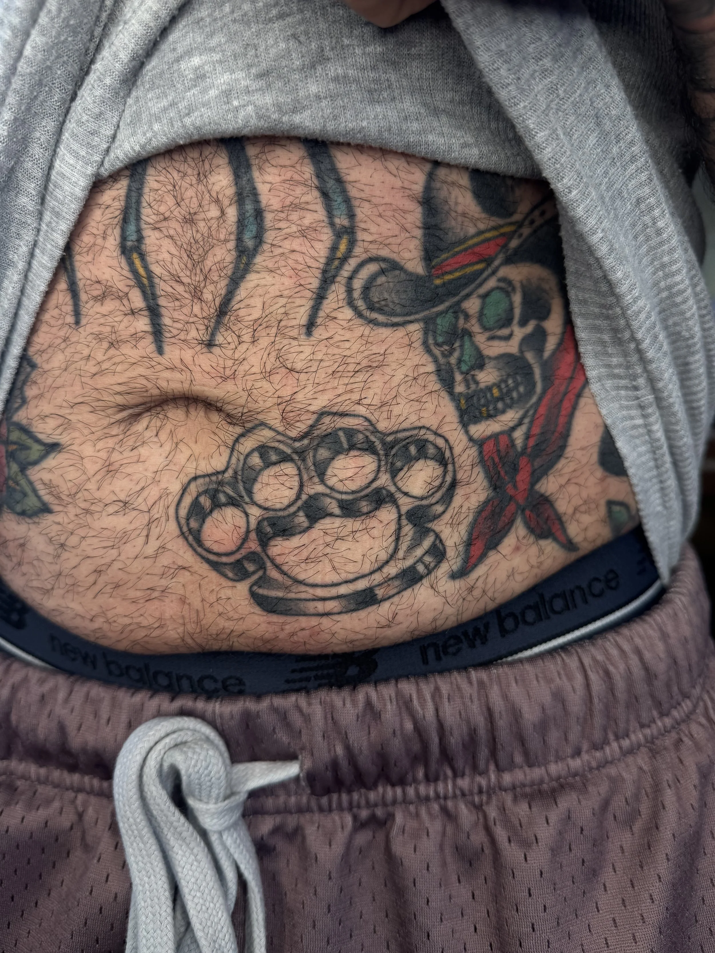 Tattoo artist Mel Gonzales, @theemelodic American Traditional black and gray brass knuckles tattoo on the arm at Dame of the West Tattoo in Scottsdale, Arizona.