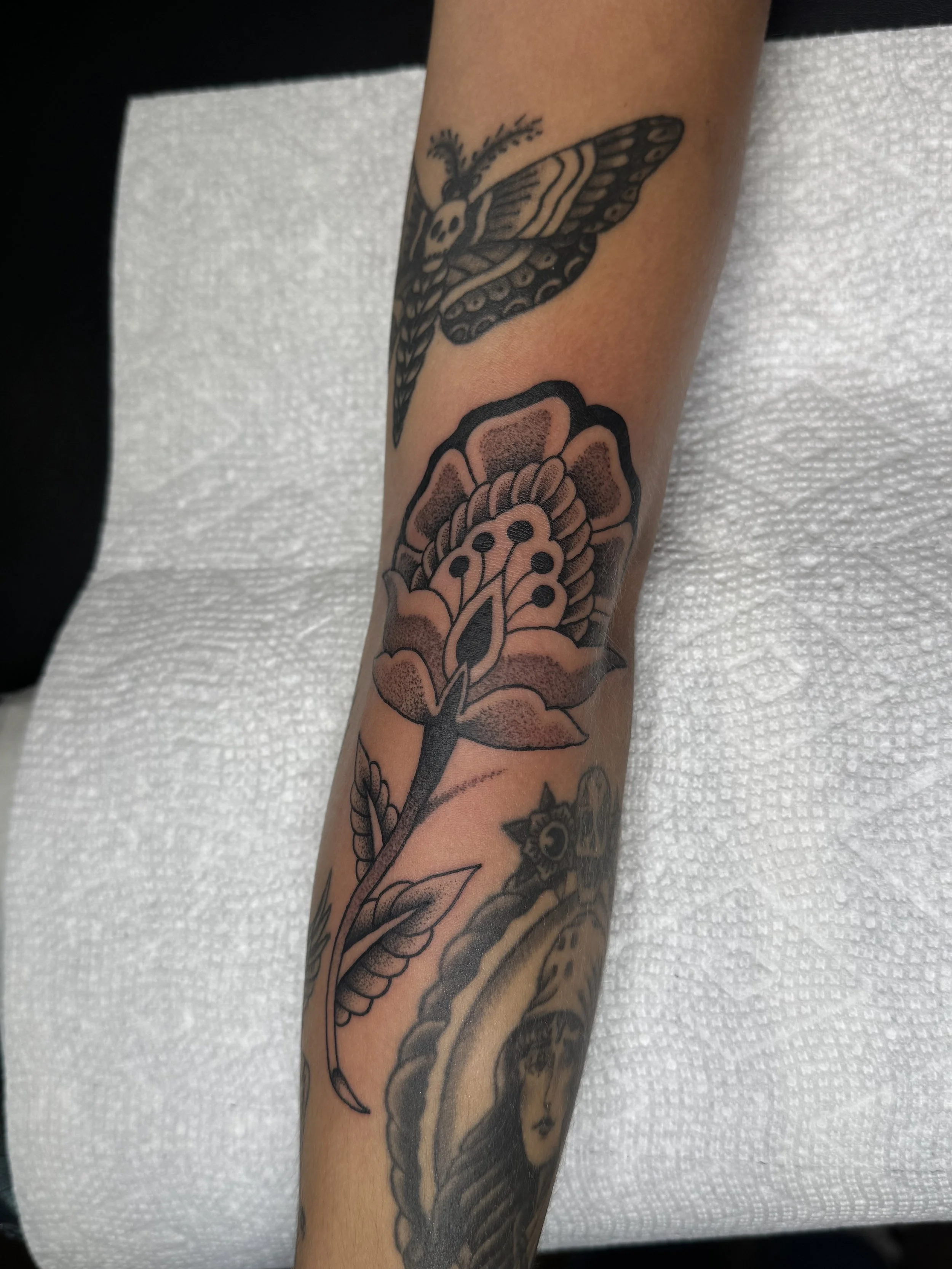 Tattoo artist Mel Gonzales, @theemelodic black and gray ornamental flower tattoo on the arm at Dame of the West Tattoo in Scottsdale, Arizona.
