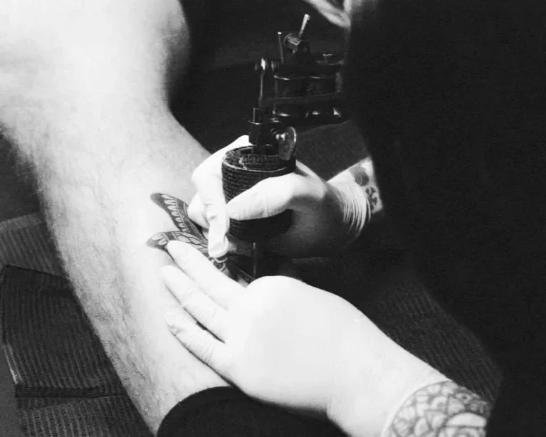 A client of Dame of the West Tattoo located in the heart of Old Town Scottsdale, Arizona is getting a tattoo on their leg by professional tattoo artist, Morgan Gatekeeper.
