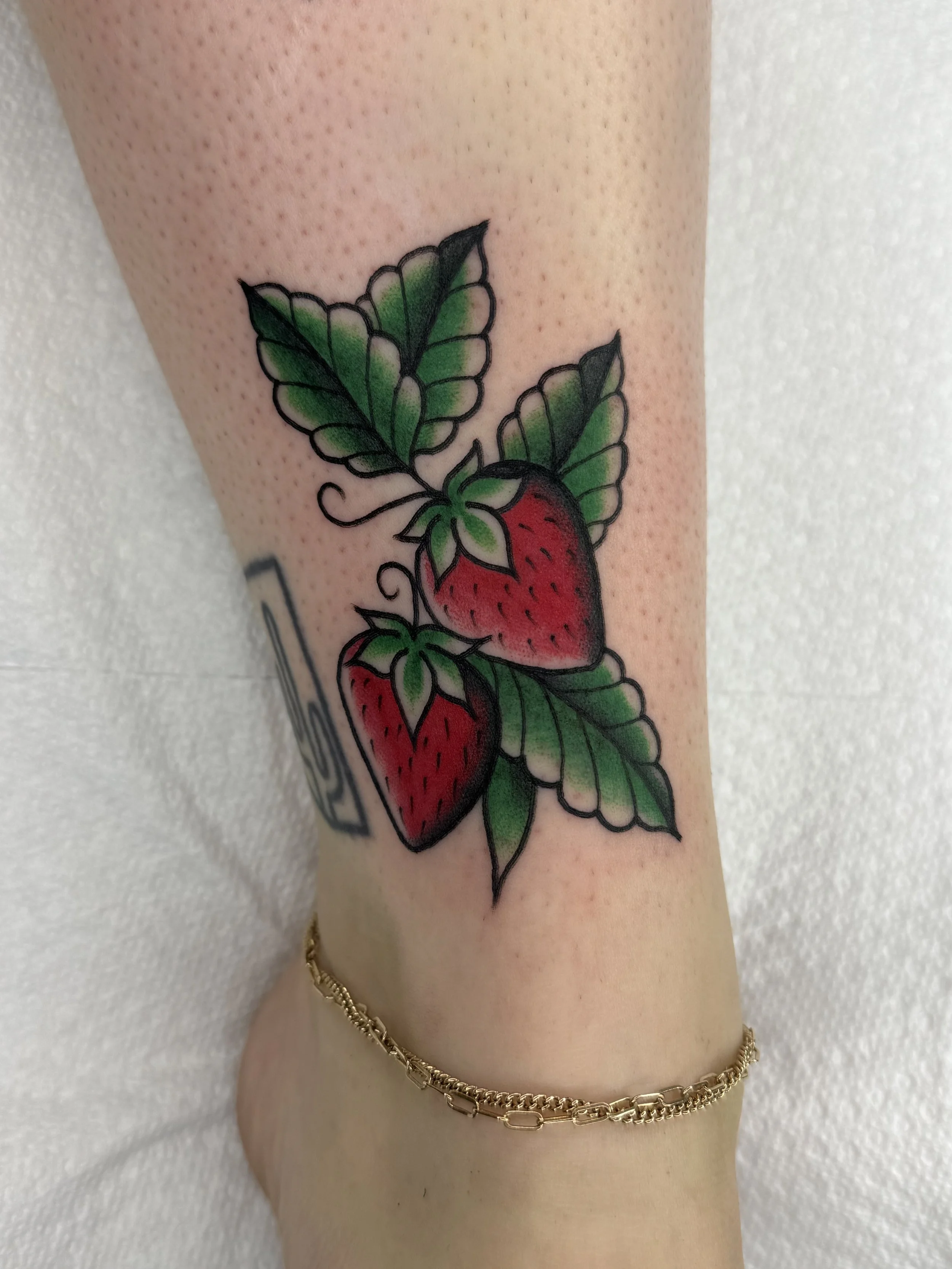 Tattoo artist Mel Gonzales, @theemelodic American Traditional style full color strawberry tattoo on the ankle at Dame of the West Tattoo in Scottsdale, Arizona.