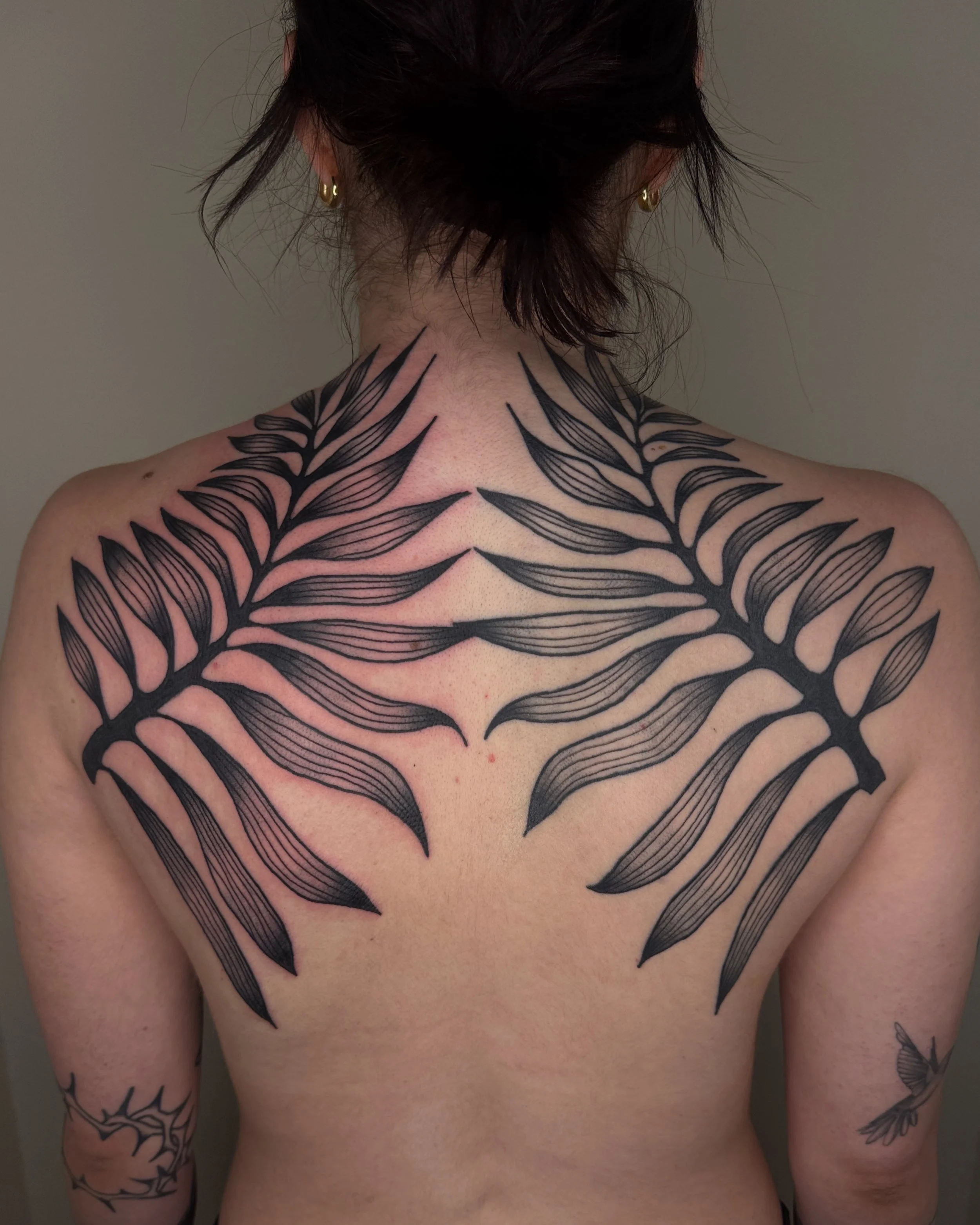 Tattoo artist Mel Gonzales, @theemelodic black and gray large leaf tattoo on the back at Dame of the West Tattoo in Scottsdale, Arizona.