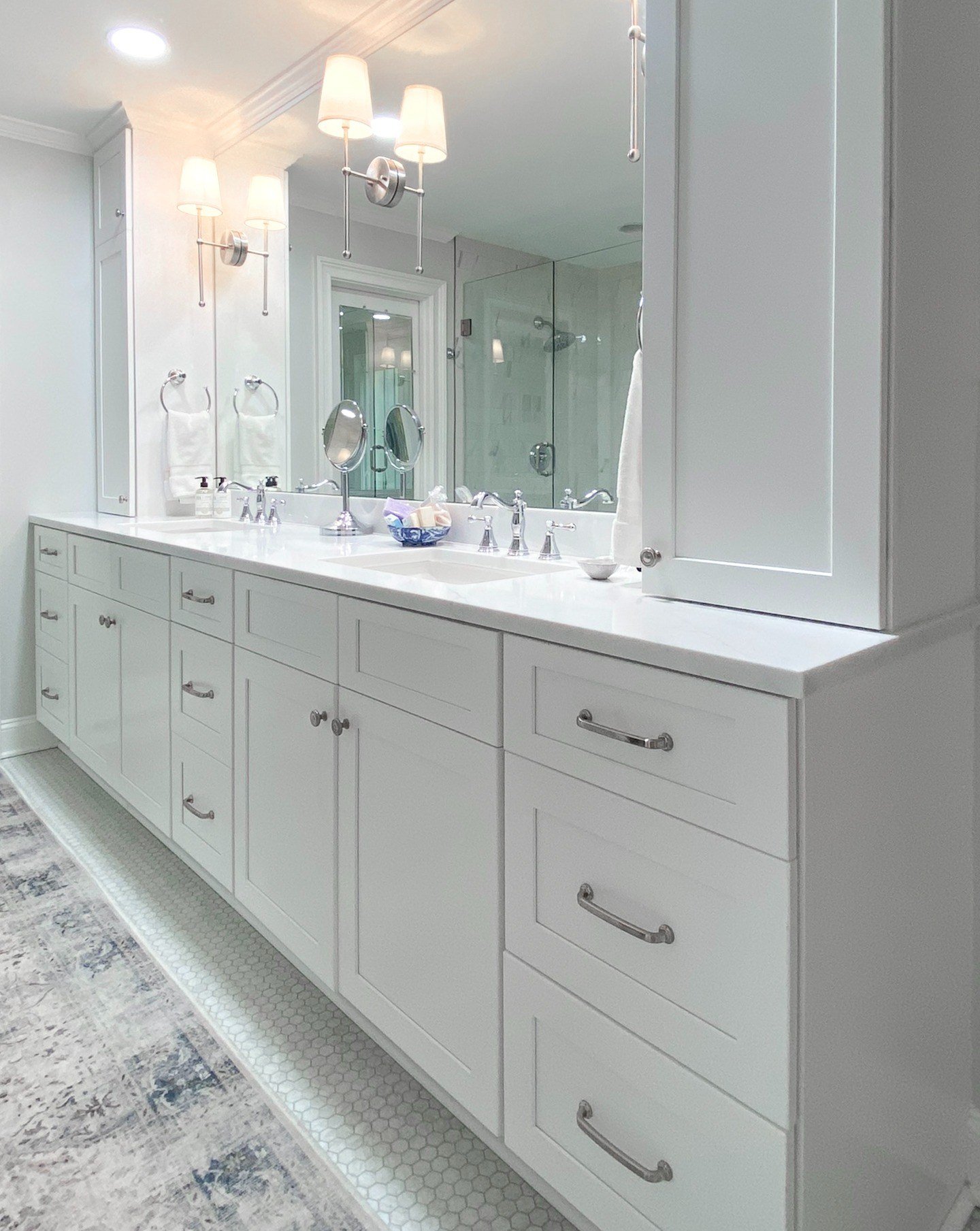 This custom double vanity features shaker-style cabinetry, quartz countertops, polished chrome fixtures, and expansive mirrors that brighten the entire primary bathroom.