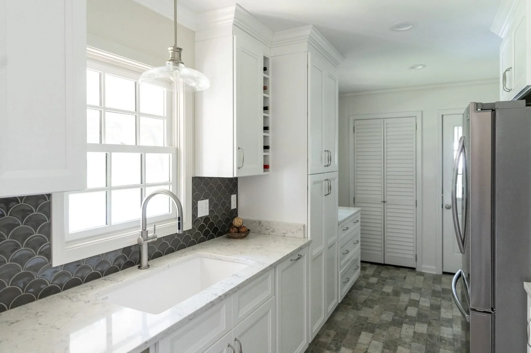 Bright white kitchen remodel with quartz countertops, custom cabinetry, farmhouse sink, and decorative tile backsplash in Germantown, TN.