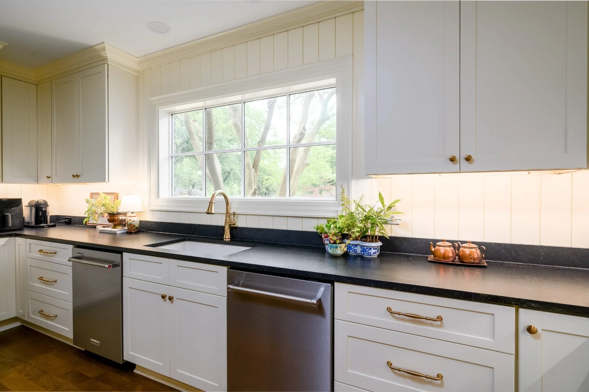 Brass kitchen faucet and farmhouse sink beneath oversized picture window