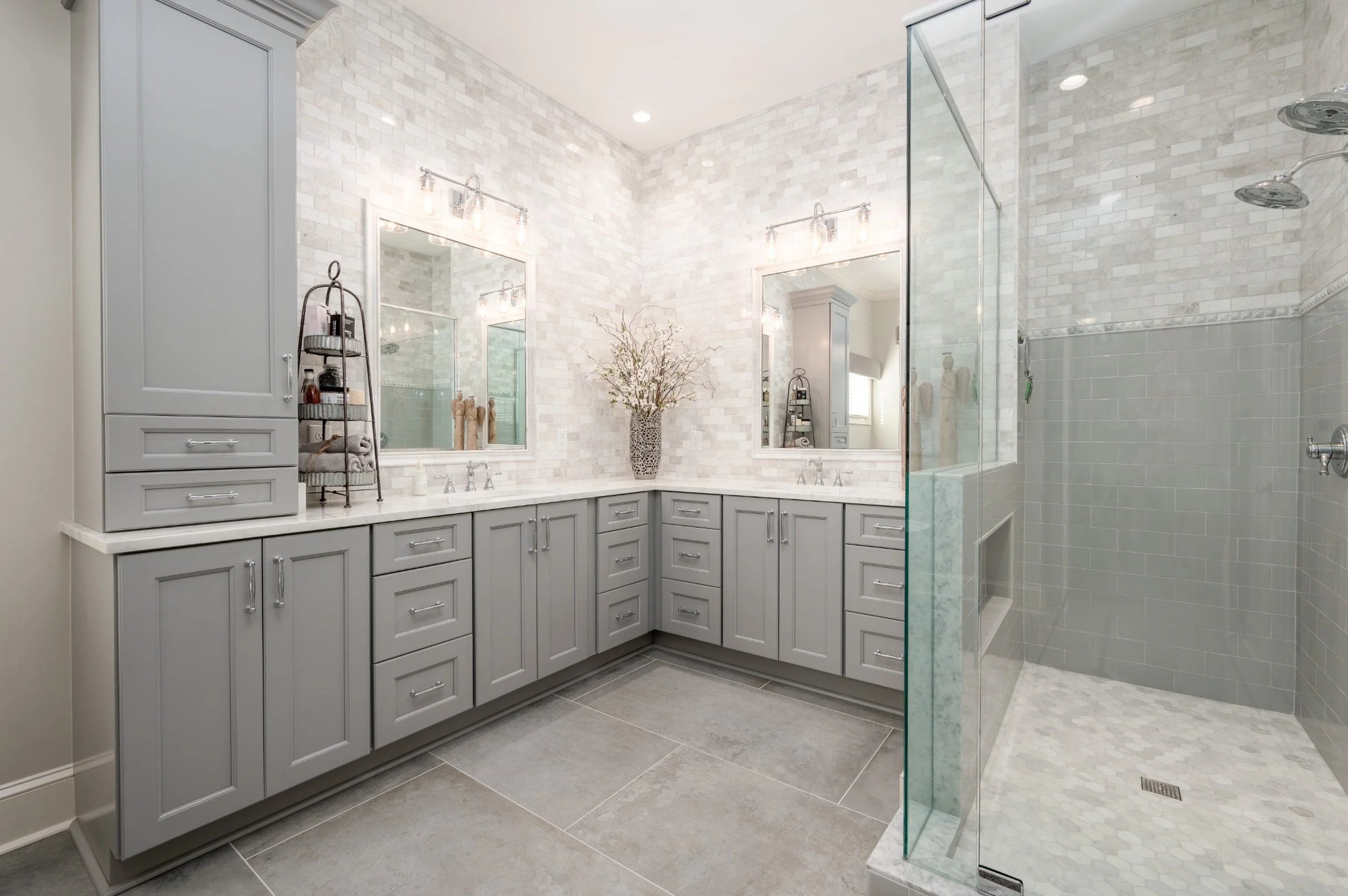 Custom bathroom remodel in Avent Ridge, Collierville TN featuring gray shaker cabinets, marble-look wall tile, double vanity sinks, quartz countertops, and a frameless glass shower.