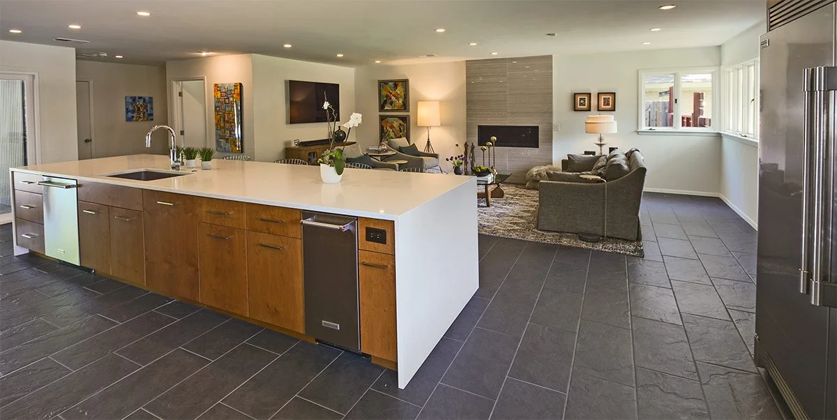 Open-concept living area with a kitchen island and a cozy seating area, large windows, and modern decor.