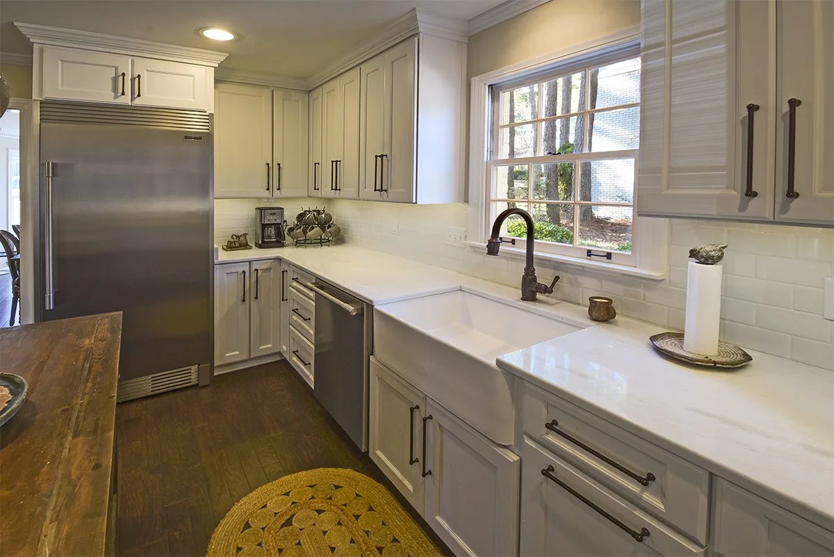 White kitchen with cabinetry, a window over the sink, and stainless steel appliances.