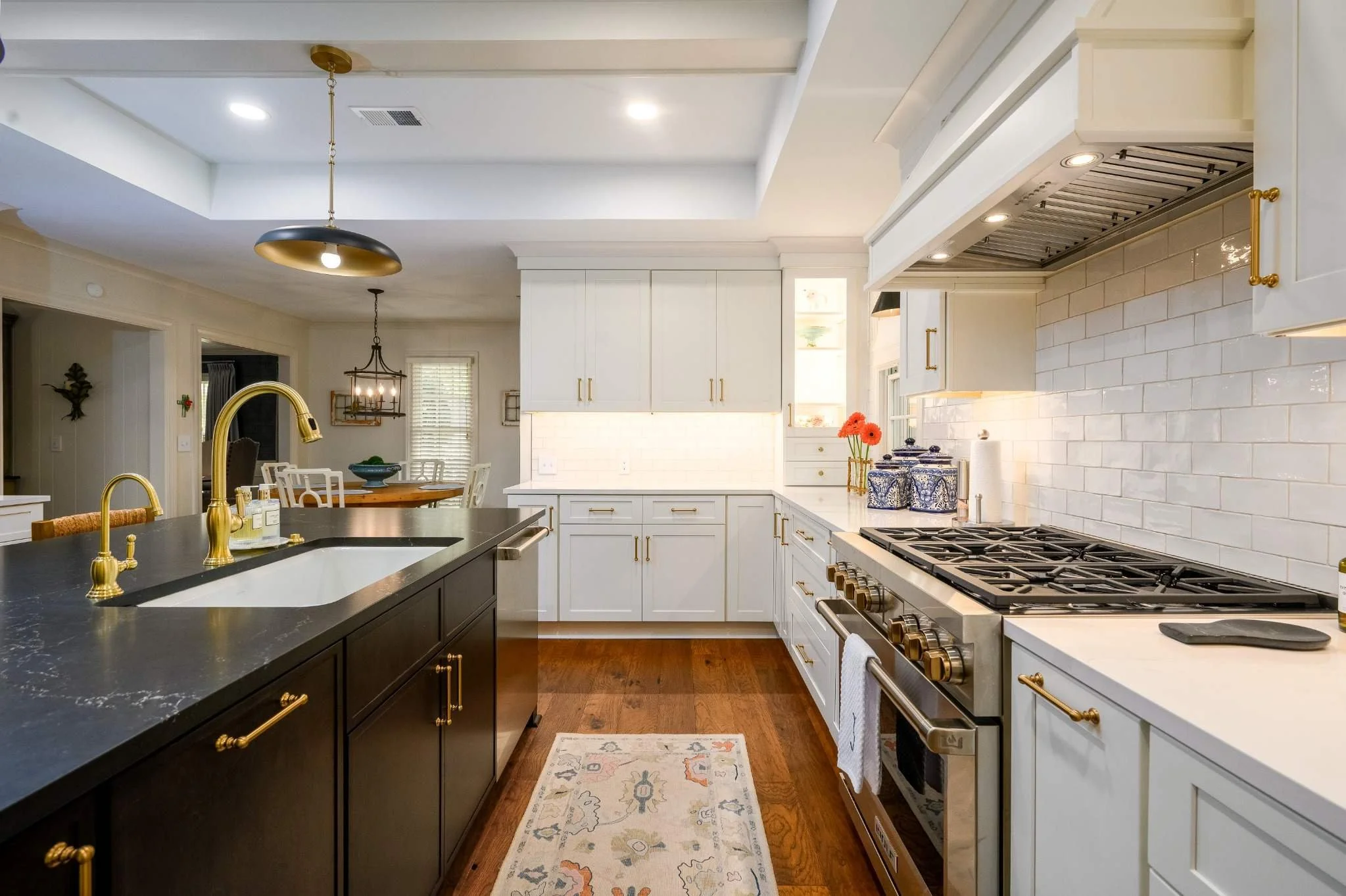 Custom East Memphis kitchen remodel with white shaker cabinets, dark wood island, white tile backsplash, brass hardware and hardwood floors.