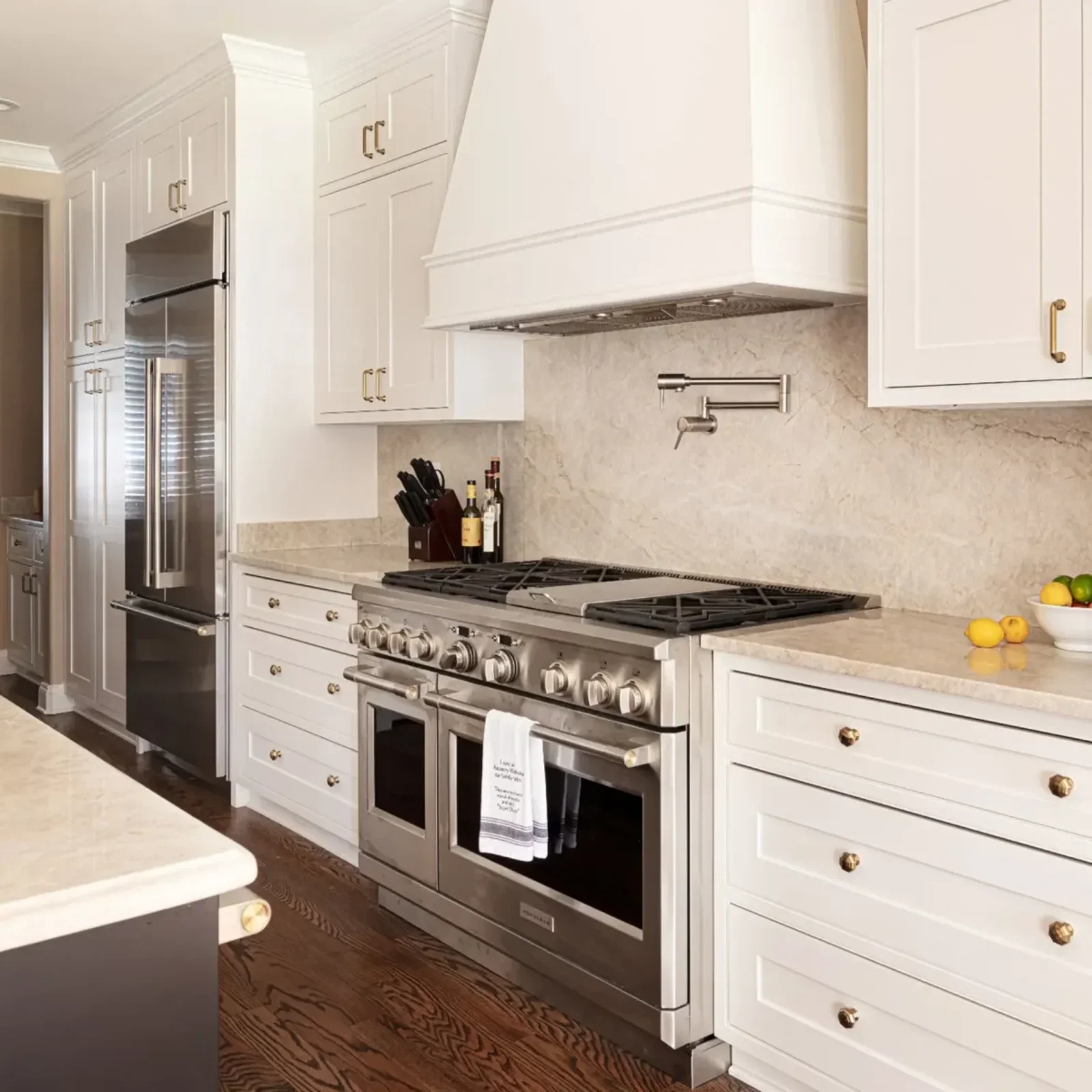 Custom kitchen remodel featuring white shaker cabinets, a professional-grade stainless steel gas range, marble backsplash, custom vent hood, quartz countertops, and dark hardwood flooring.