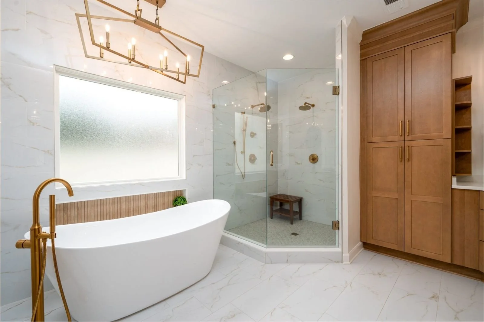 Clean lines, soft marble-look tile, and warm metallic accents give this Halle Plantation bathroom remodel a bright and timeless aesthetic.