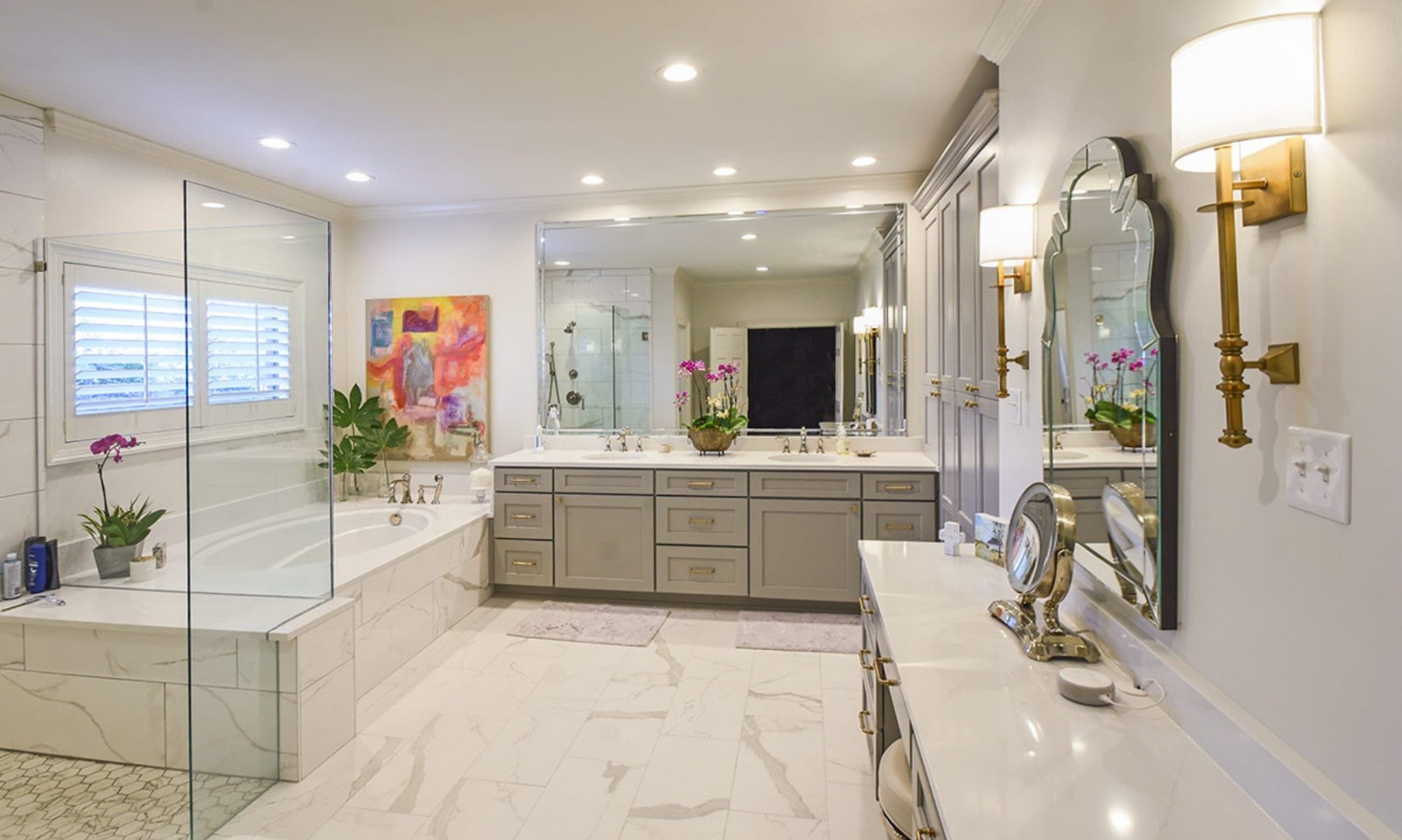 Luxury primary bathroom remodel in Germantown, Tennessee featuring a soaking tub, glass shower, custom double vanity, marble-look tile and brass fixtures.