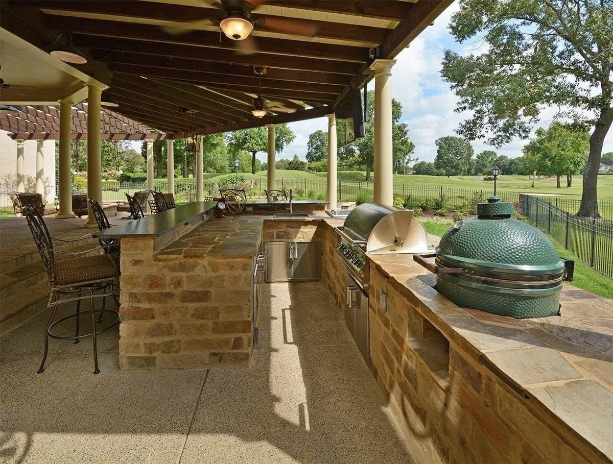 A stone-clad outdoor kitchen with bar seating designed for easy hosting and conversation.