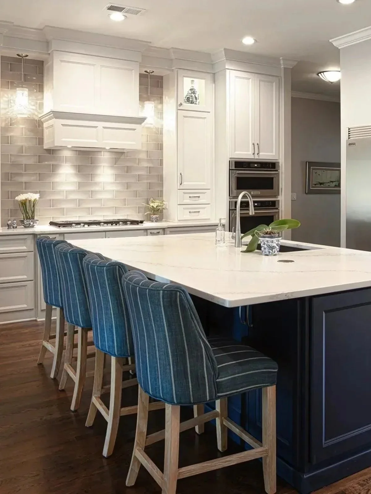 Luxury kitchen remodel with large quartz island, custom cabinetry, subway tile backsplash, and blue upholstered bar stools in Germantown, TN.