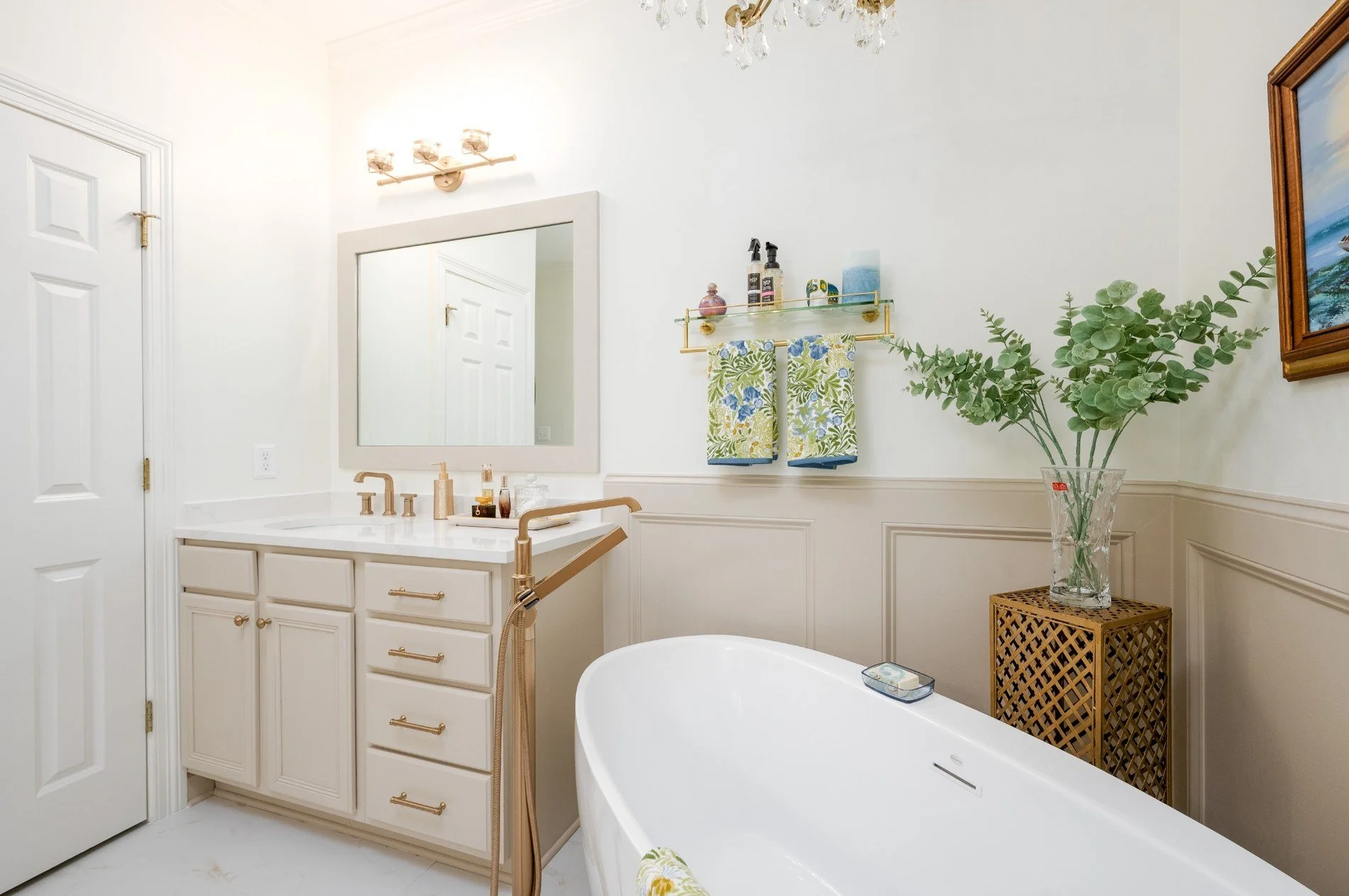 Germantown primary bathroom remodel with a freestanding tub, custom vanity, brass fixtures and decorative wall molding.