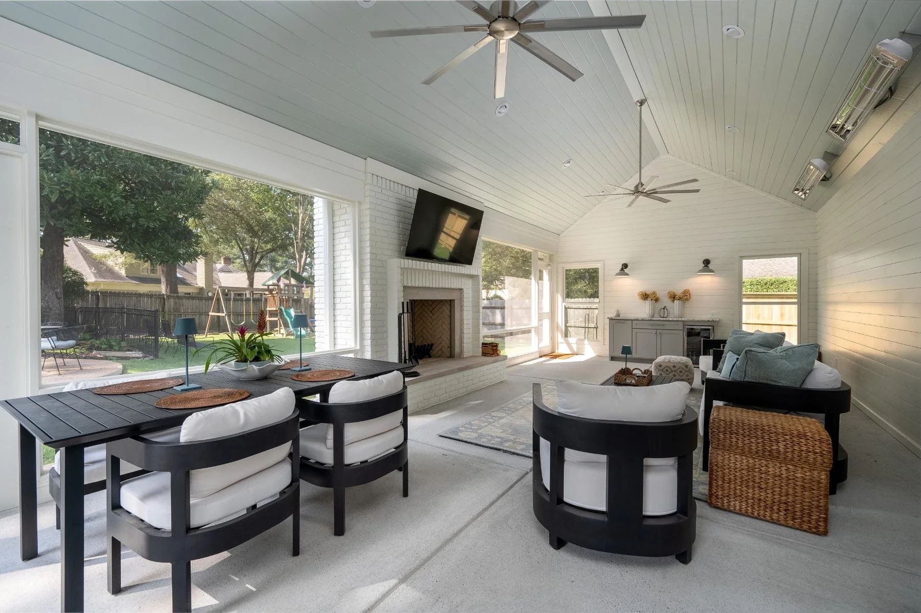Covered outdoor living area in Germantown, TN, featuring a white brick fireplace, vaulted ceiling, dining area, and comfortable seating by Robbins Construction.